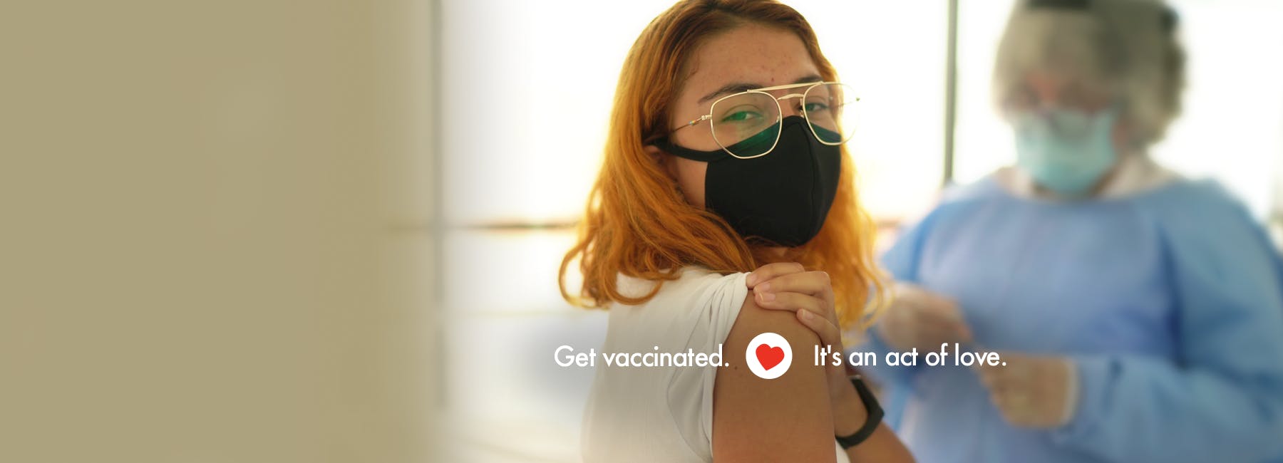 Girl with glasses and a mask showing her arm after getting a vaccine shot