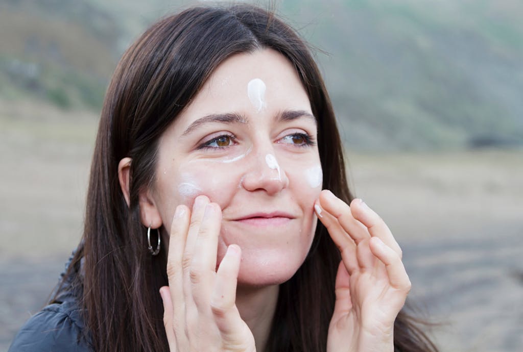 Kobieta zimą smarująca twarz kremem z filtrem