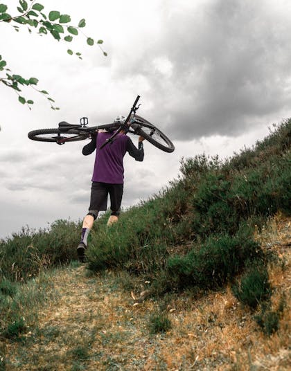 Morten der bærer sin cykel over ryggen