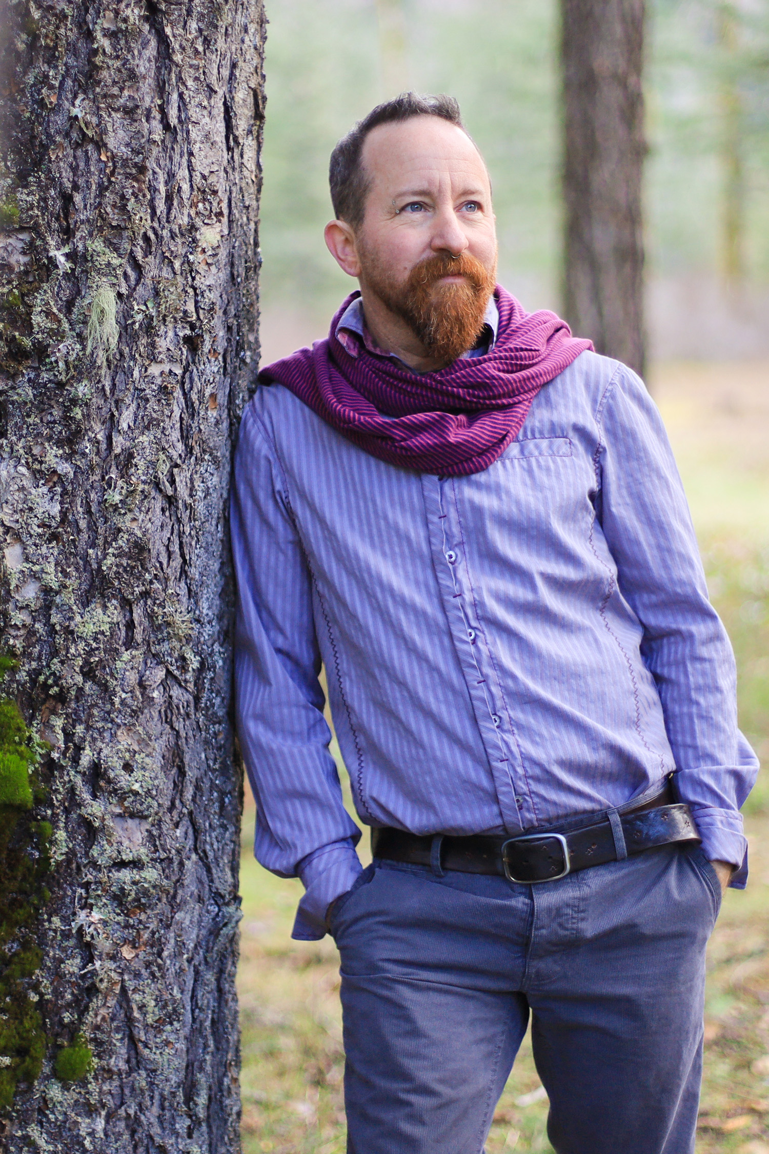 A photo of dean leaning against a beautiful tree with an approachable gaze