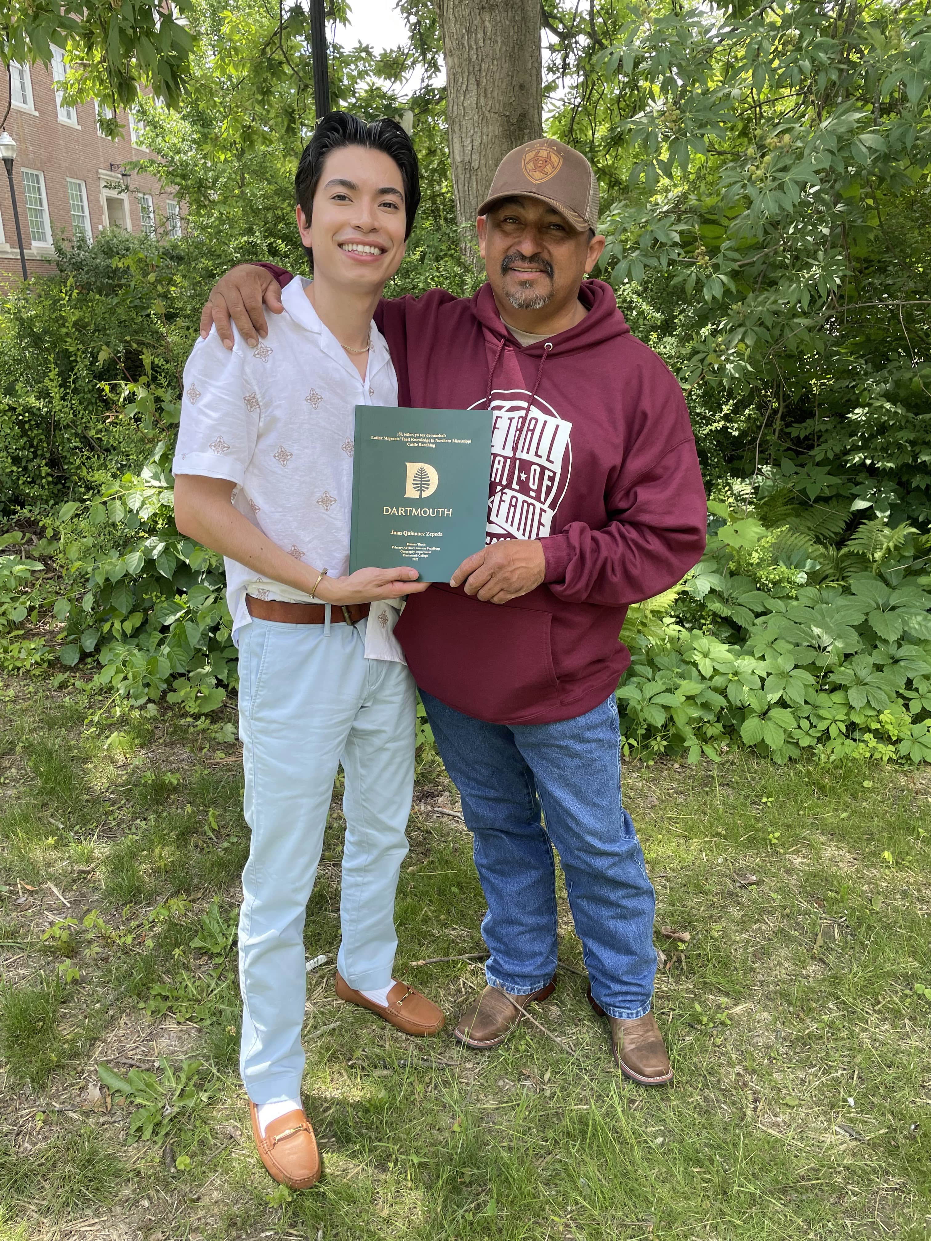 A Fuerza member holding his Dartmouth diploma with his dad