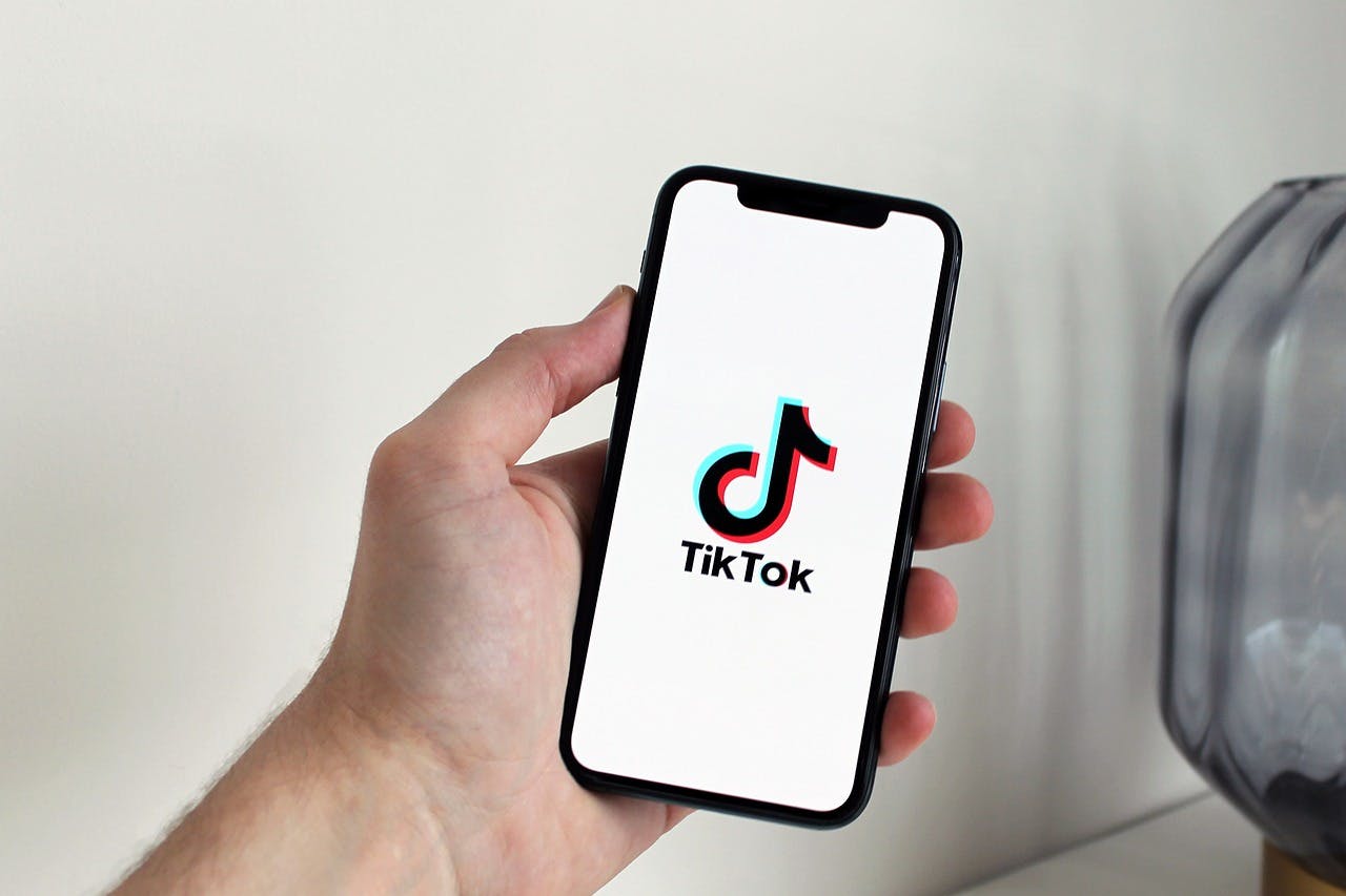 Left Hand holding an Iphone with the TikTok Logo on screen