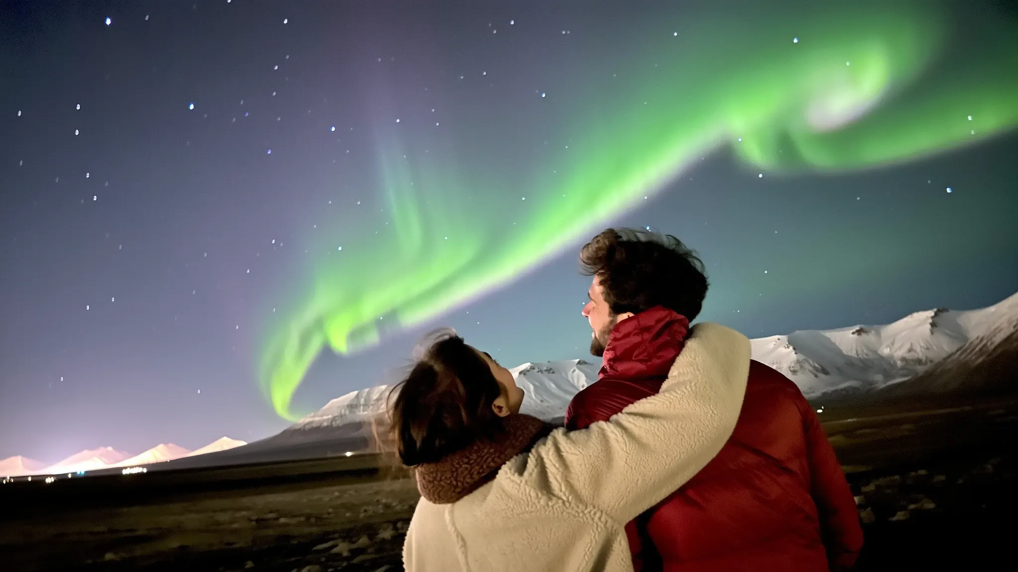 A happy couple watching the Northern Lights dancing in the sky