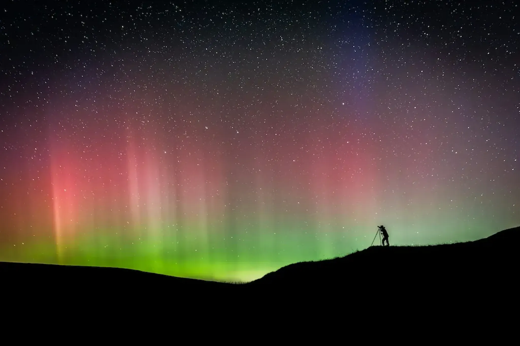 A photograph taking a photo of the red aurora. Image by Jonny Gios from Unsplash
