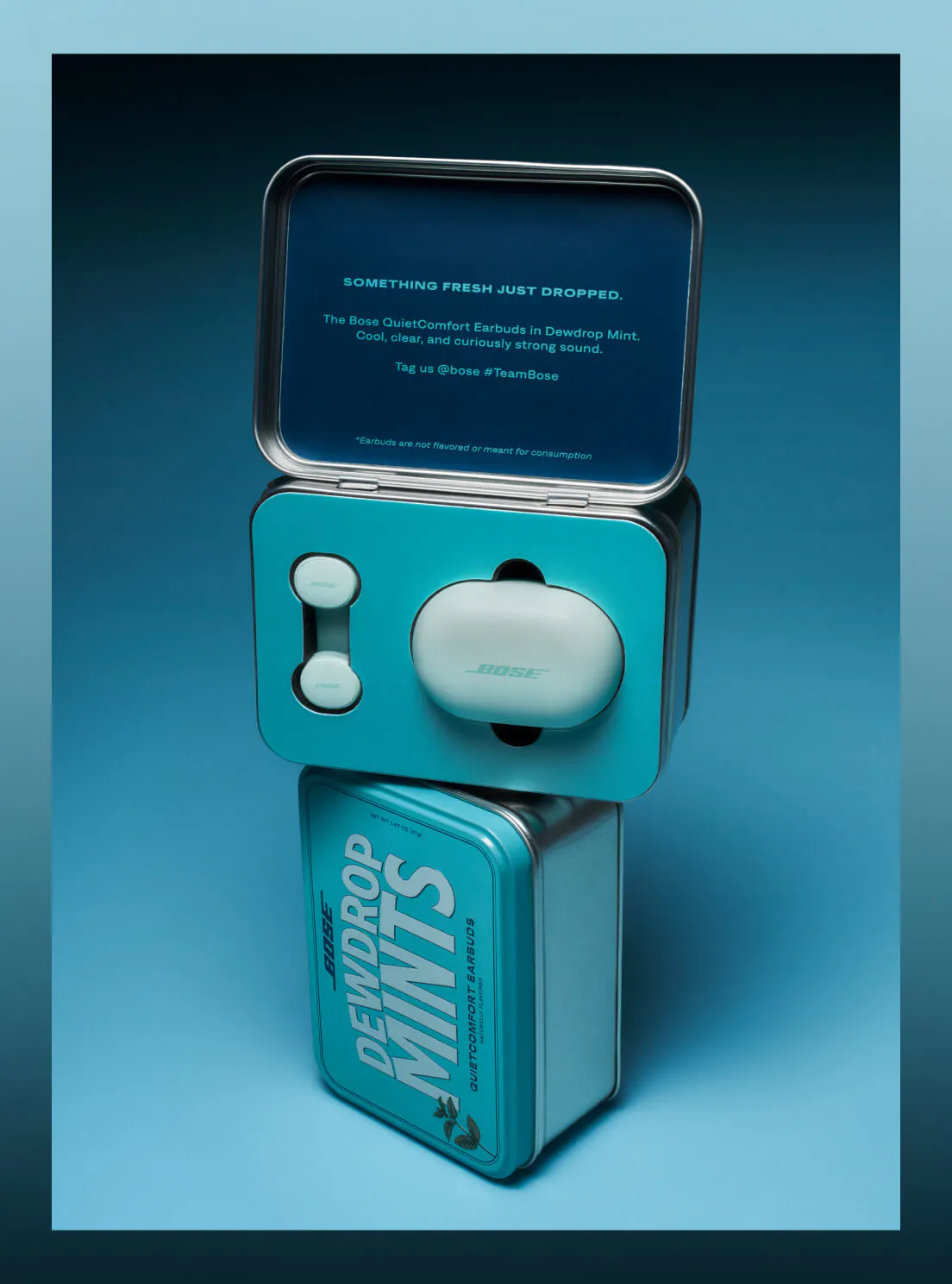 the open seeding tin stacked on top of the closed Dewdrop Mints tin, with the charging case and individual earbuds displayed inside the upper tray.