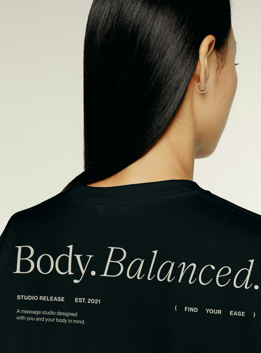 woman wearing black tee shirt showing backside with white text saying BODY. BALANCE. on it