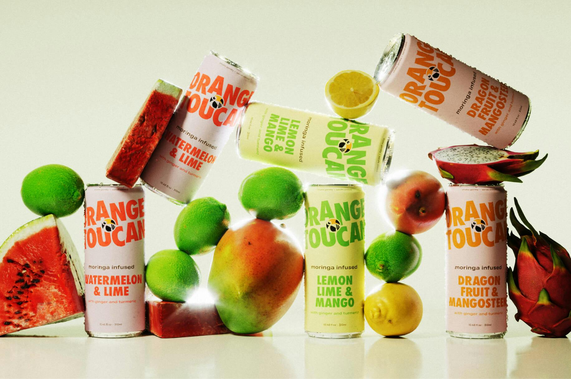 Six aluminum cans of Orange Toucan beverage stacked with various fruit