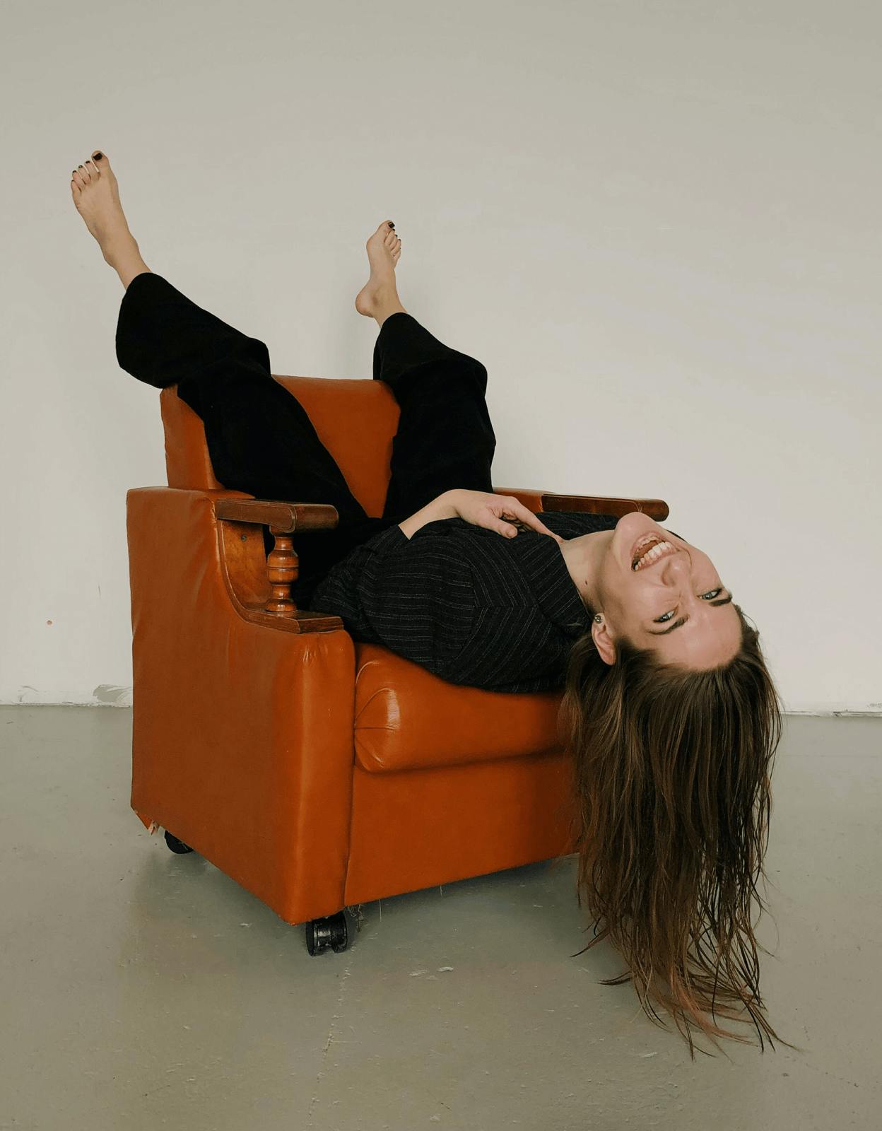 woman laying upside down in leather chair