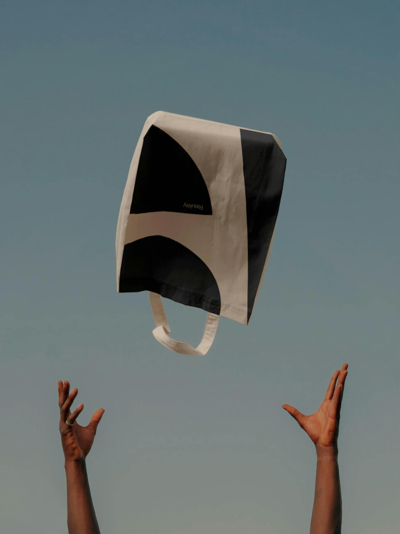 two hands throwing tote bag in air