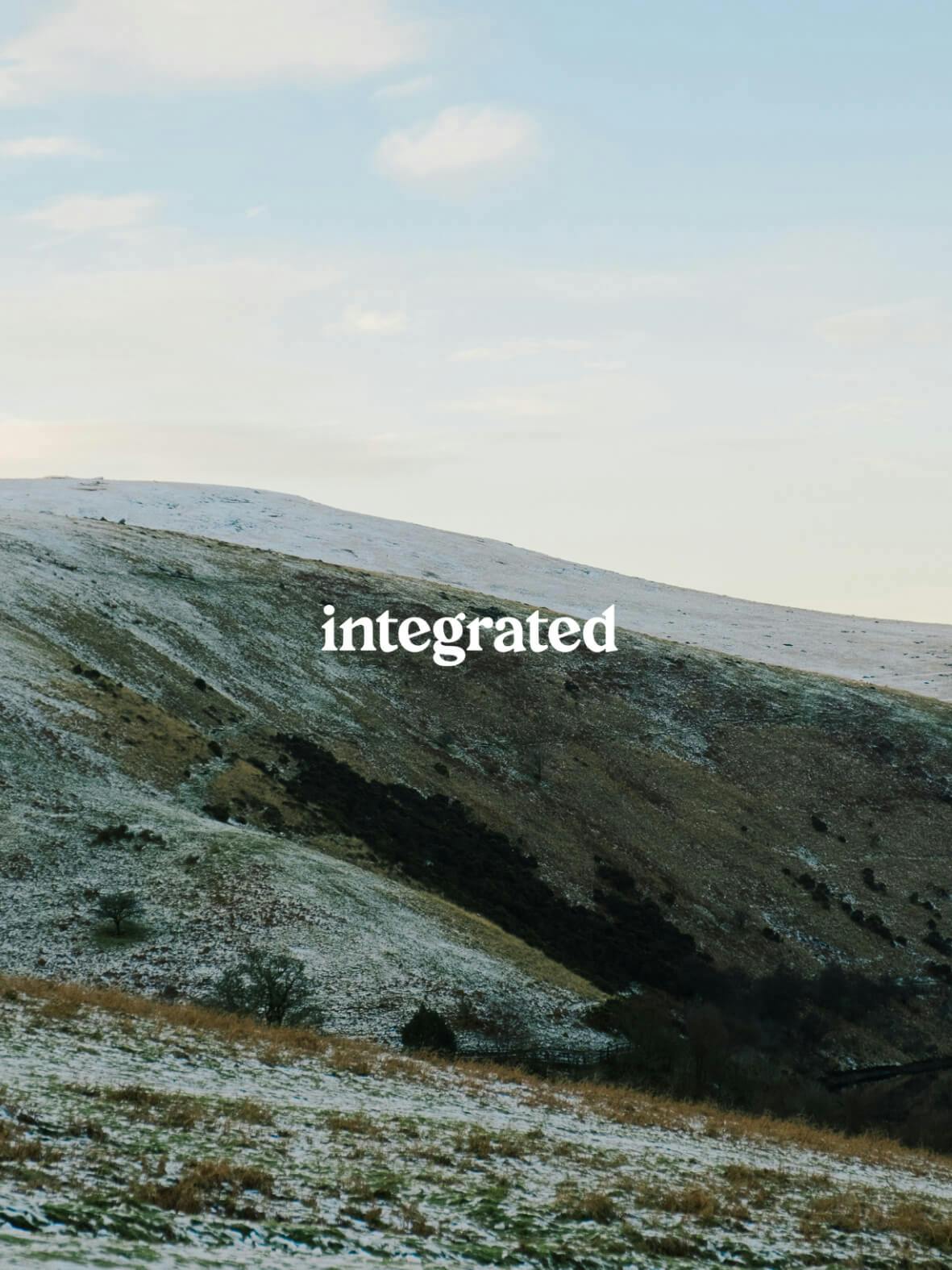 "Integrated" logo in white on mountain scene