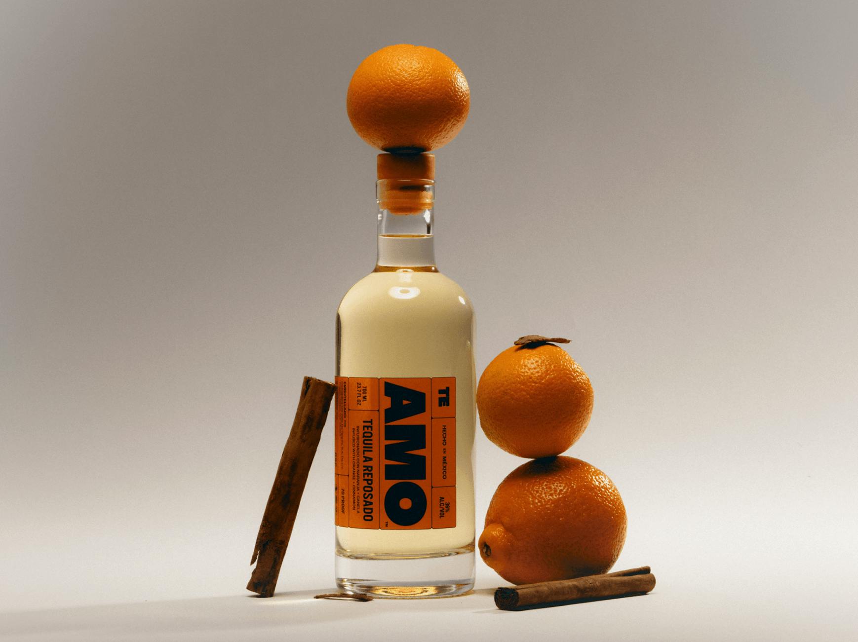 bottle of liquor next to oranges and cinnamon sticks