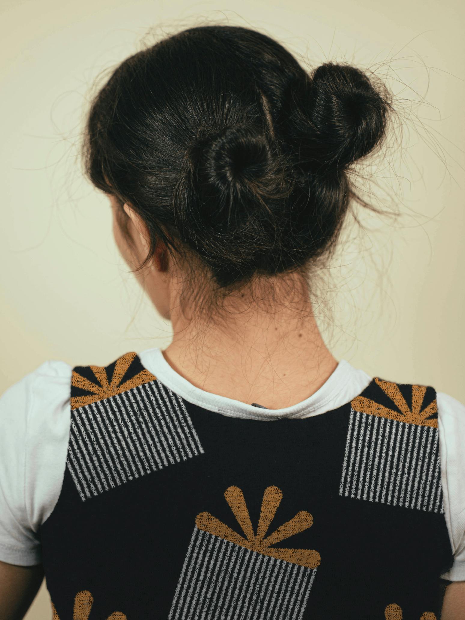 A woman from behind wearing a sweatervest