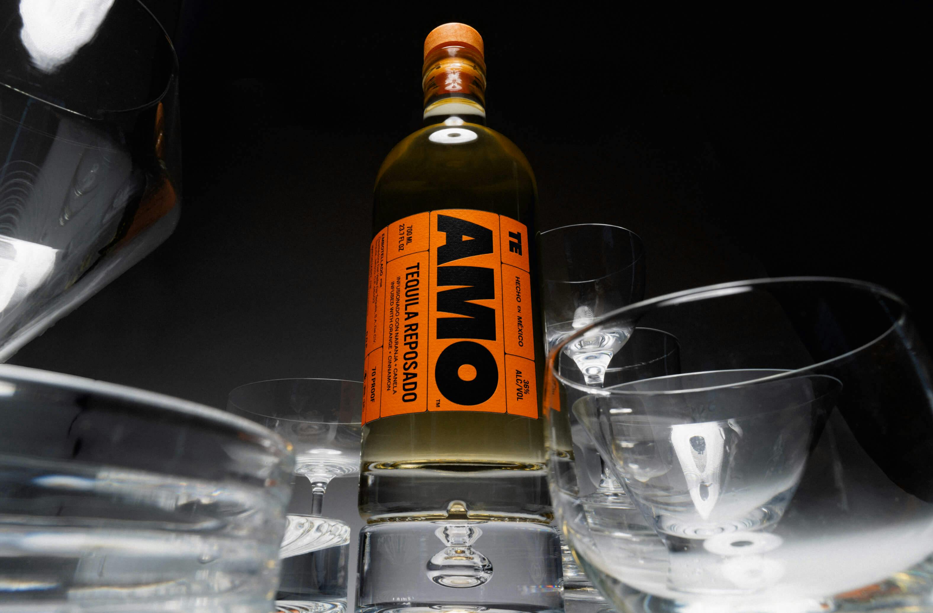 a bottle of AMO tequila surrounded by empty glasses