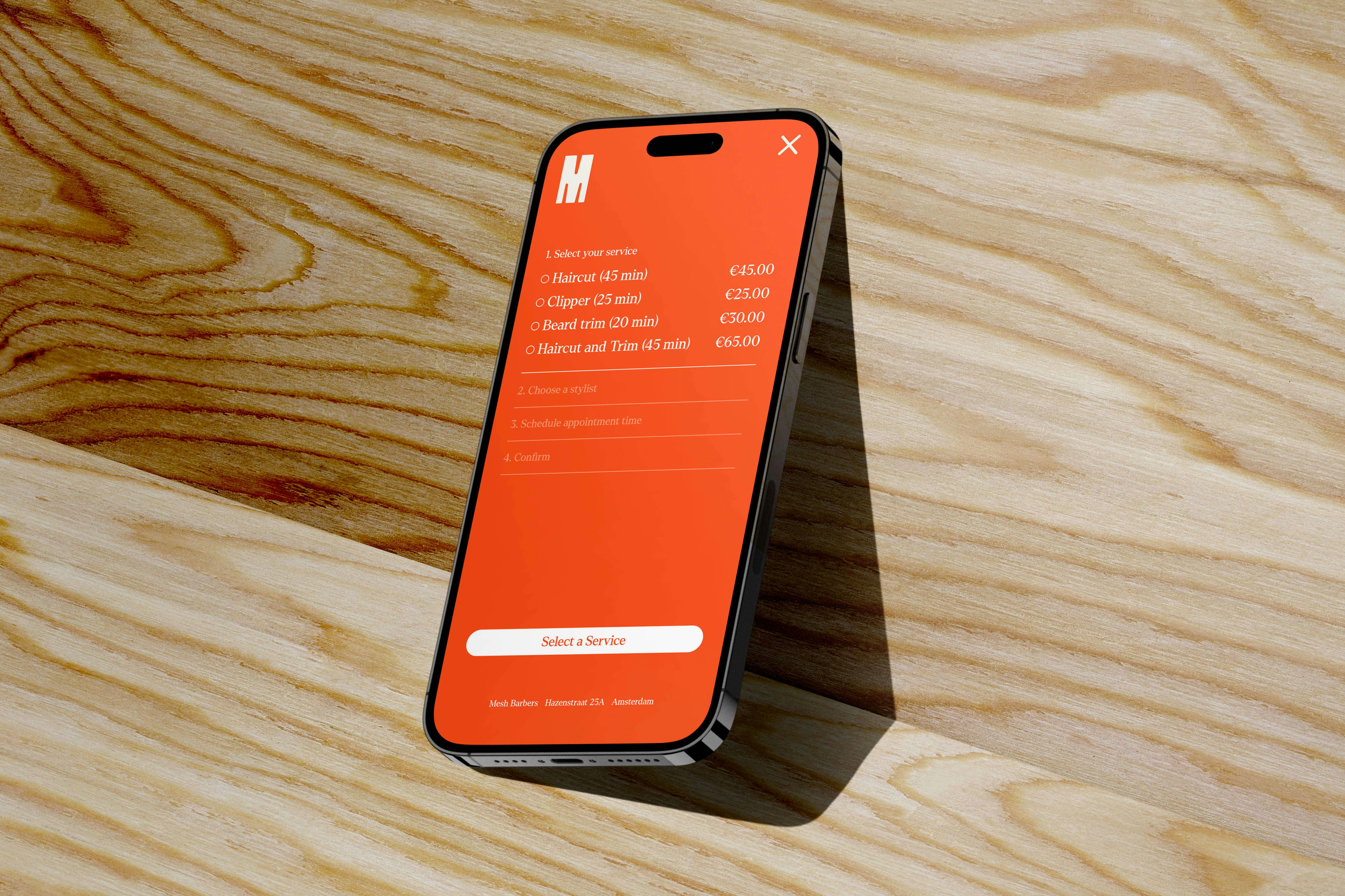 A mobile phone showing a bright orange screen for a barbershop appointment calendar