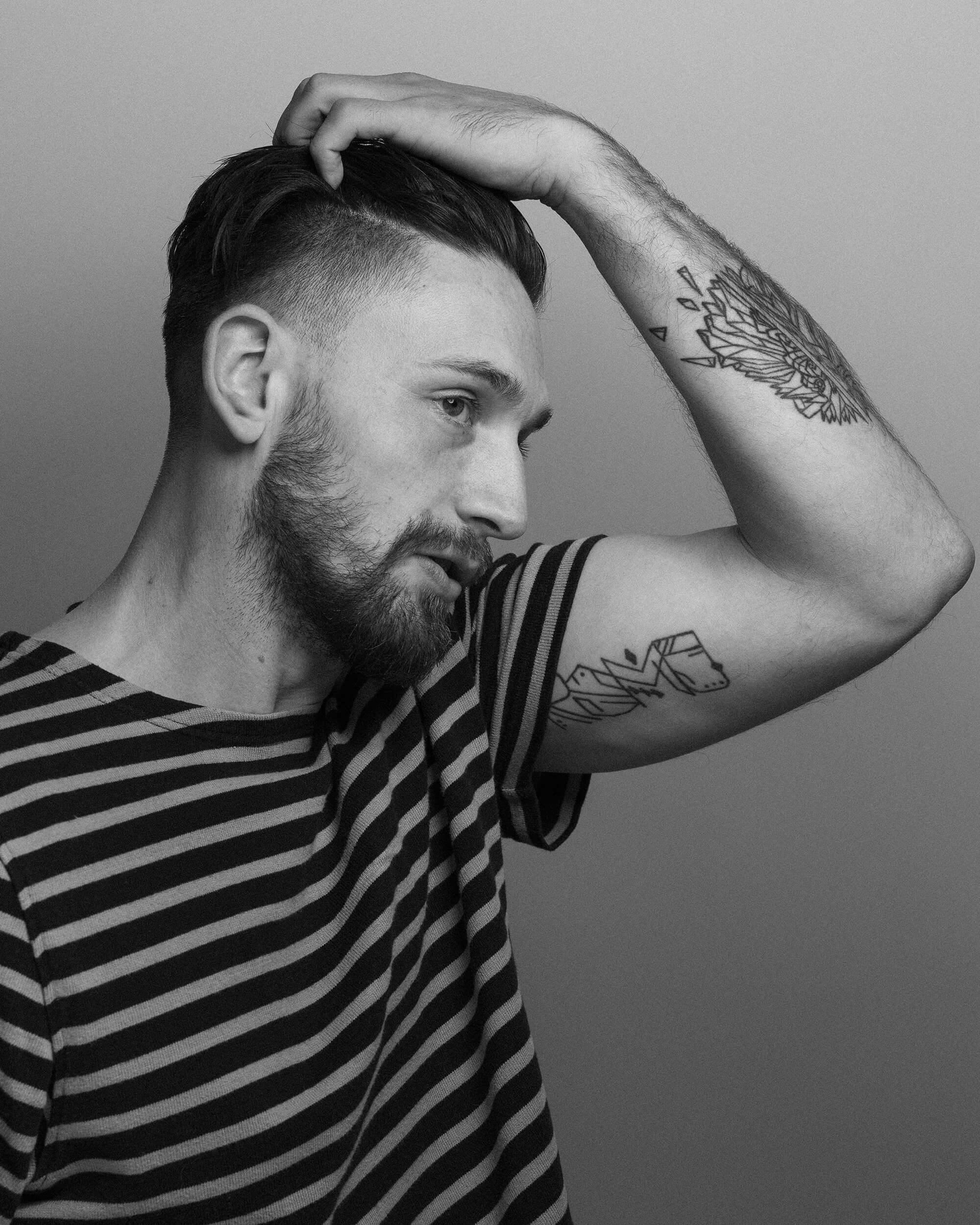 A portrait of a man combing his hair with his hands