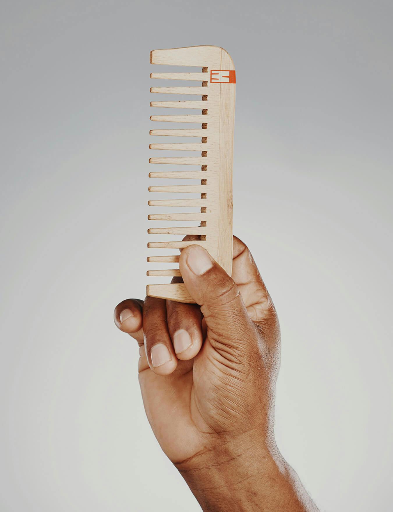 A man's hand holding a wooden comb