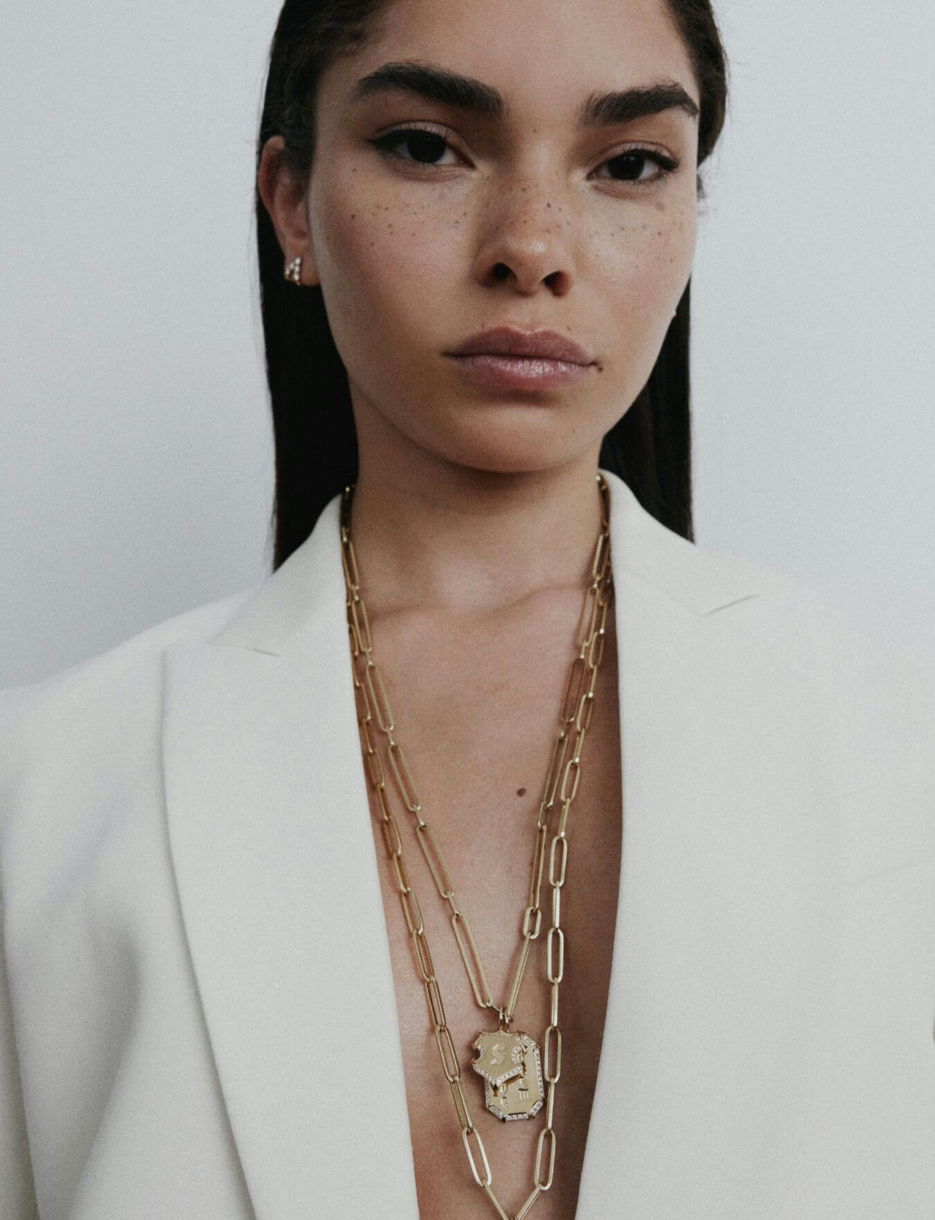 A woman wearing an open white sportcoat with a gold chain