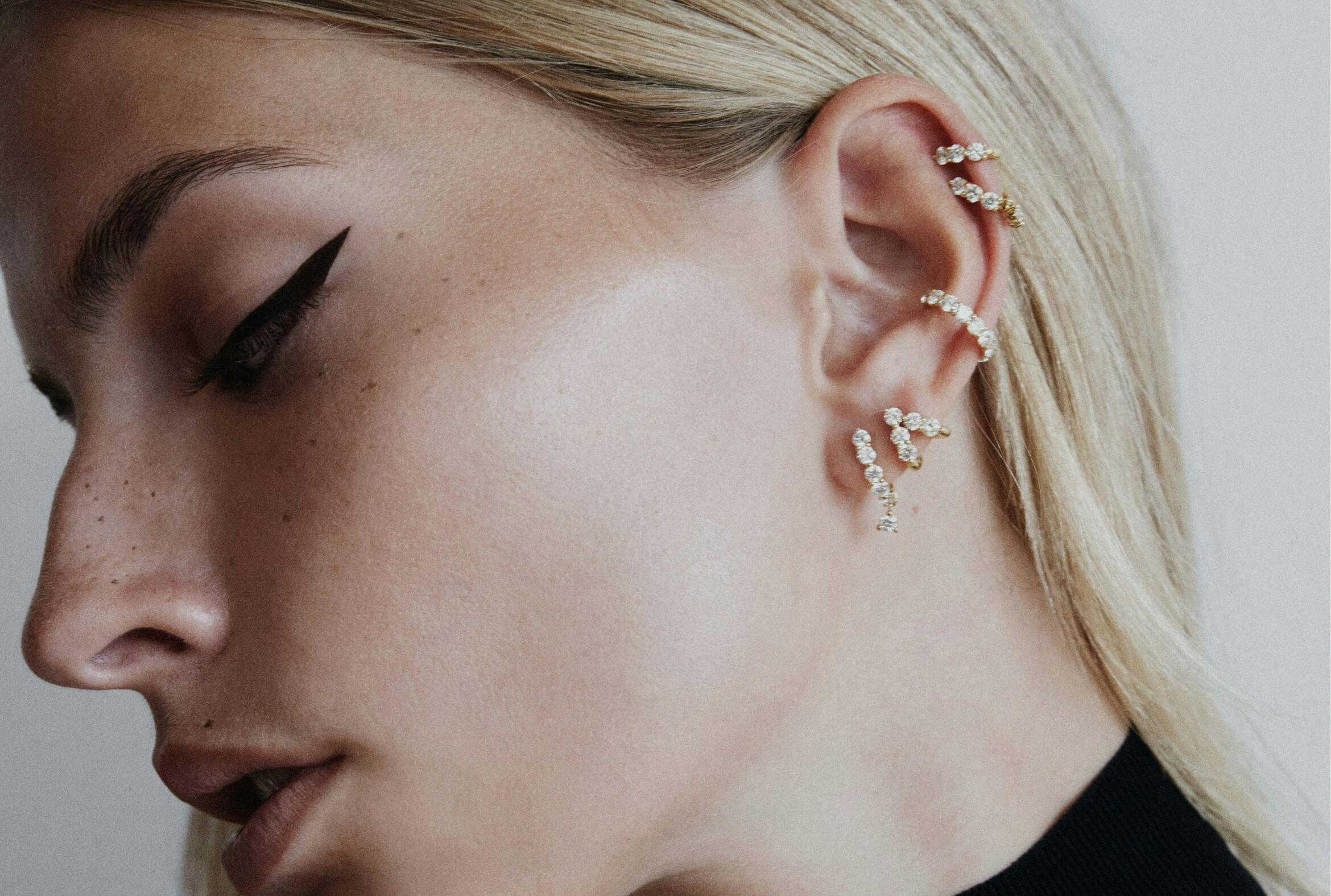 A portrait of a woman wearing multiple hoop earrings