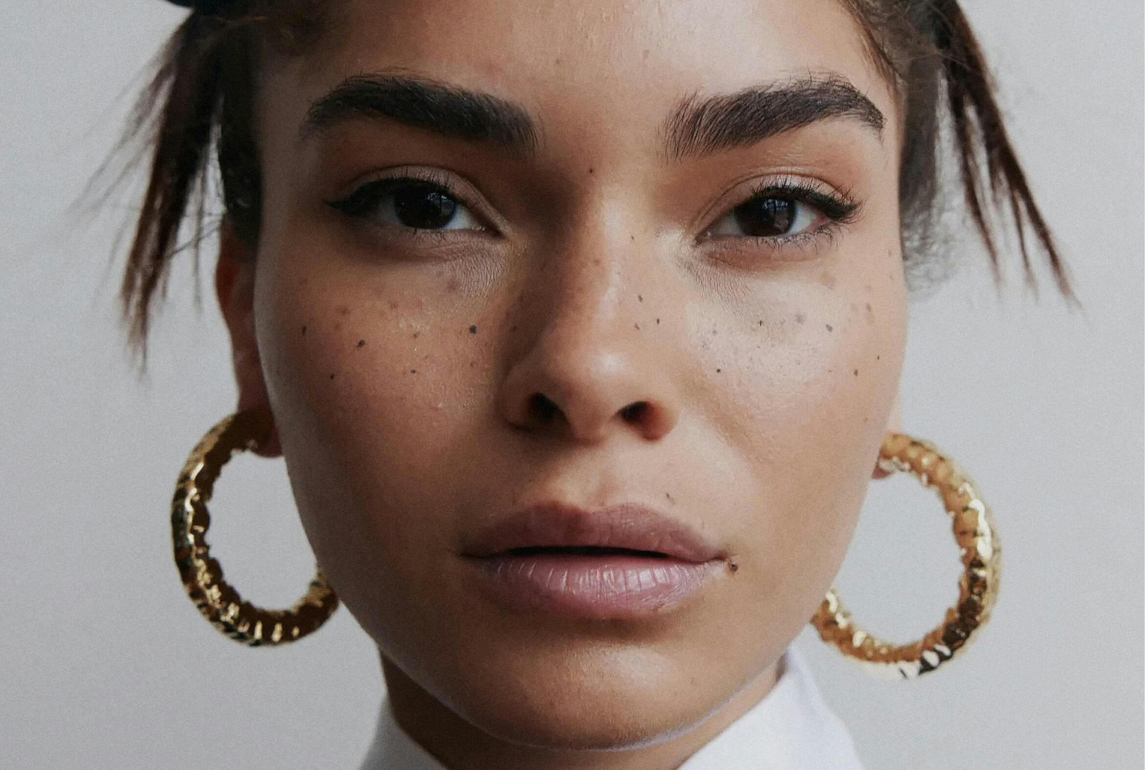 Detail portrait of woman wearing gold JENNIFER FISHER earrings