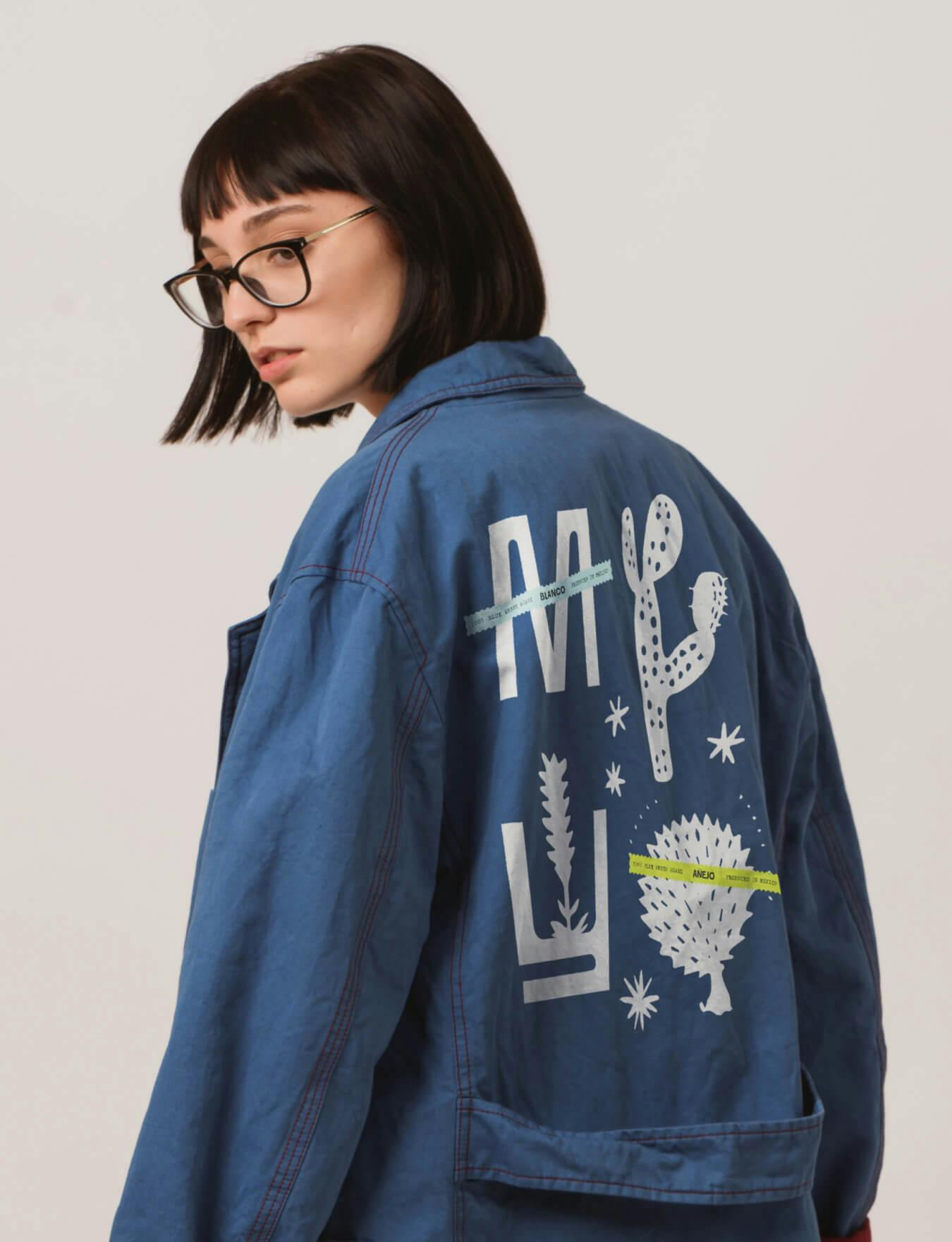 A woman wearing a denim jacket with an illustration in white on the back