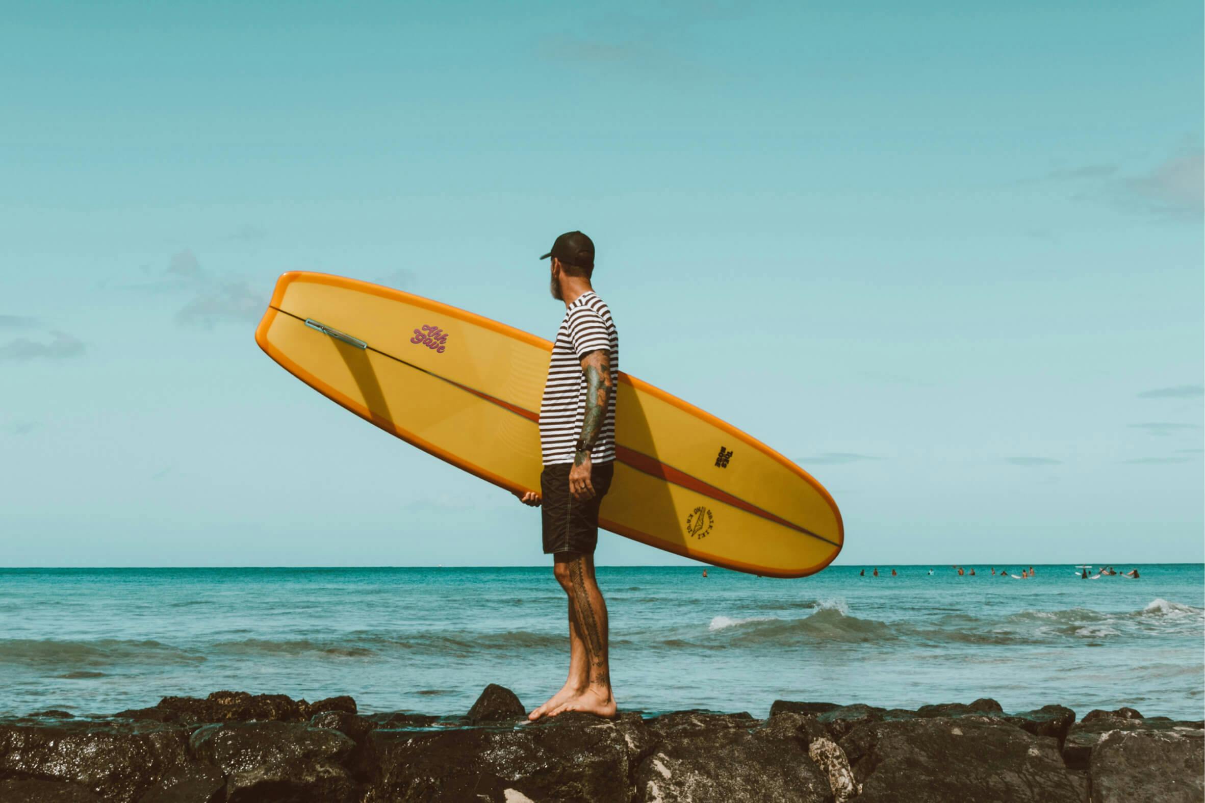 man holding surfboard on beach