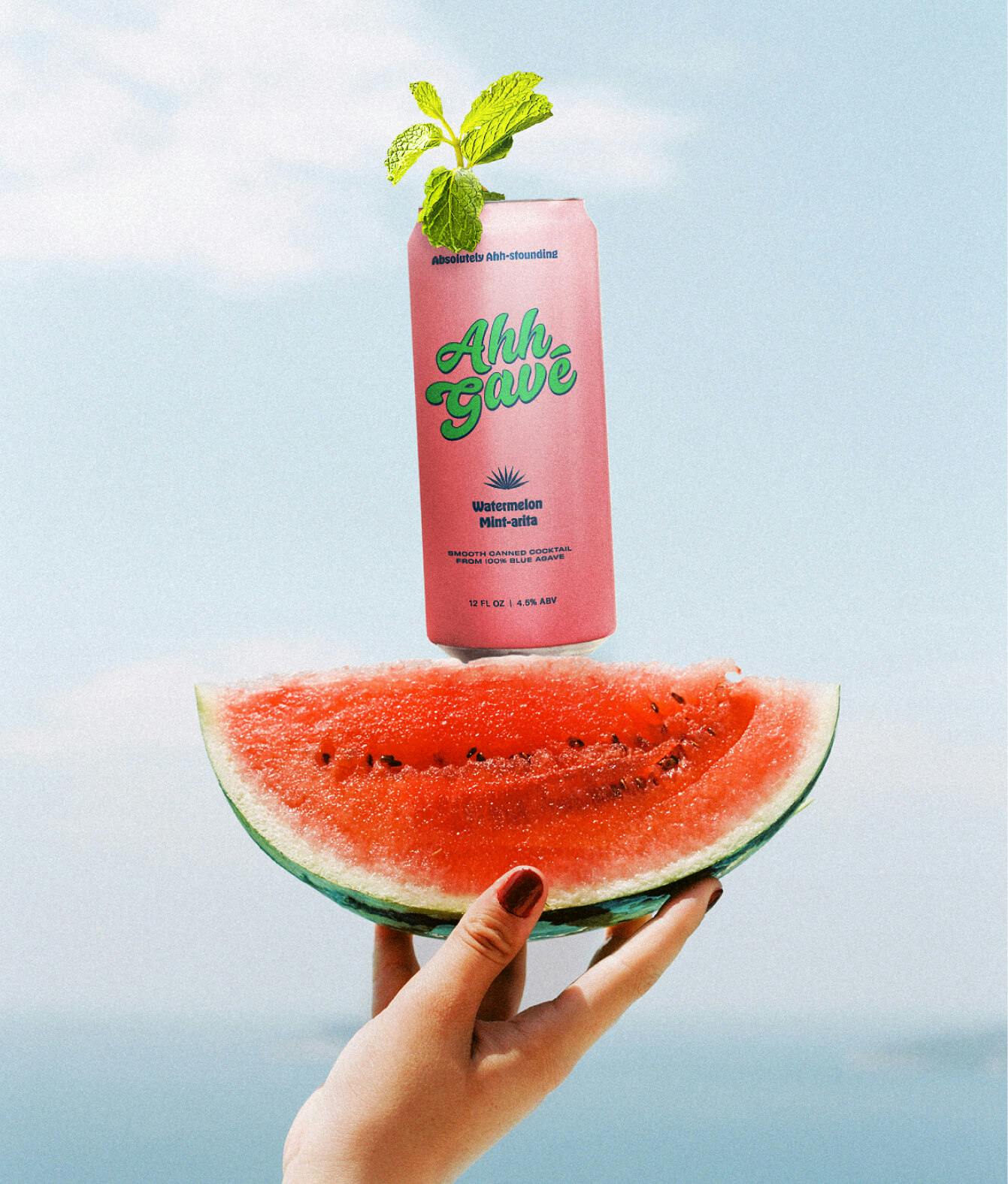 woman's hand holding slide of watermelon with beverage balancing on top