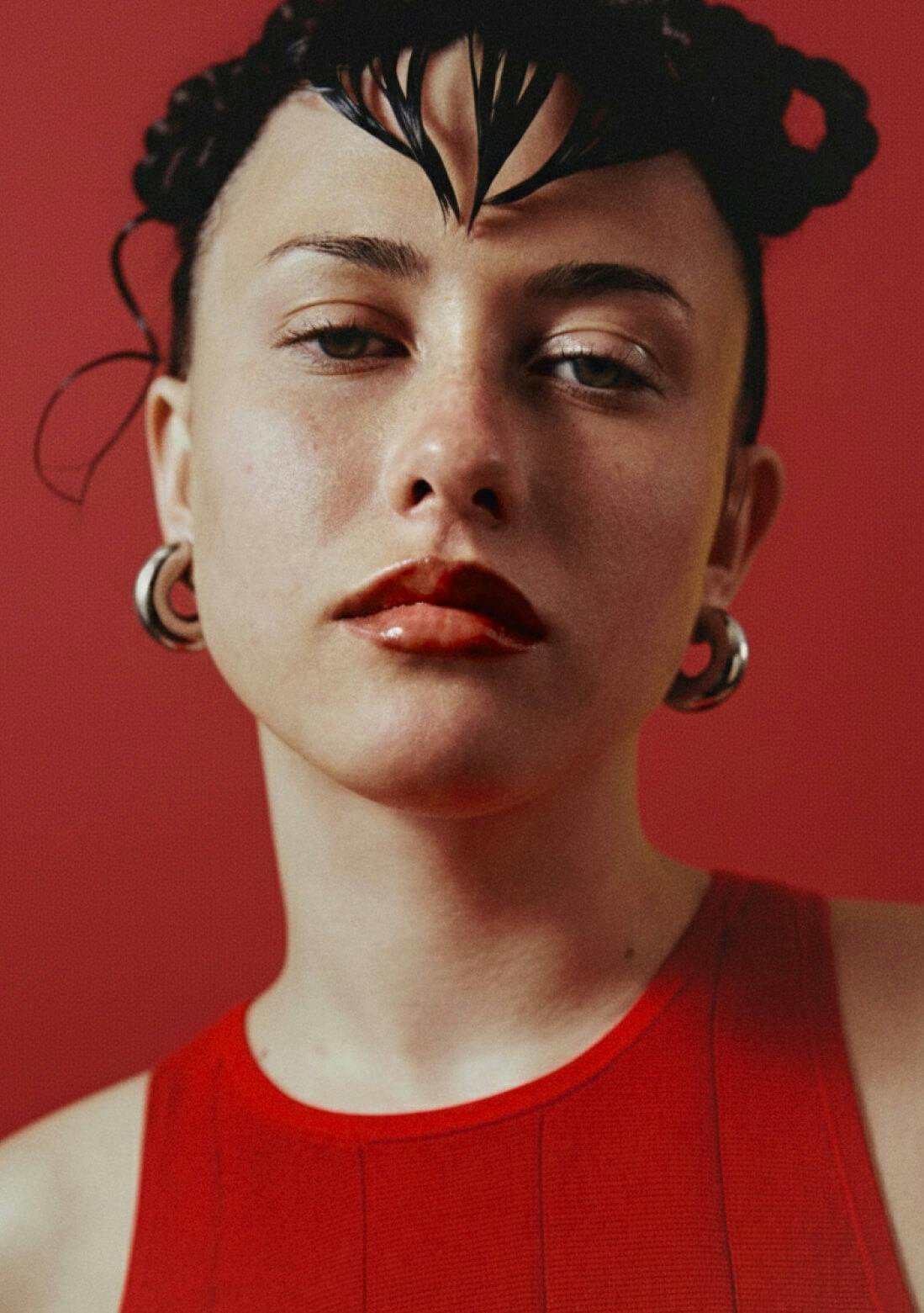 woman wearing red top in front of red background