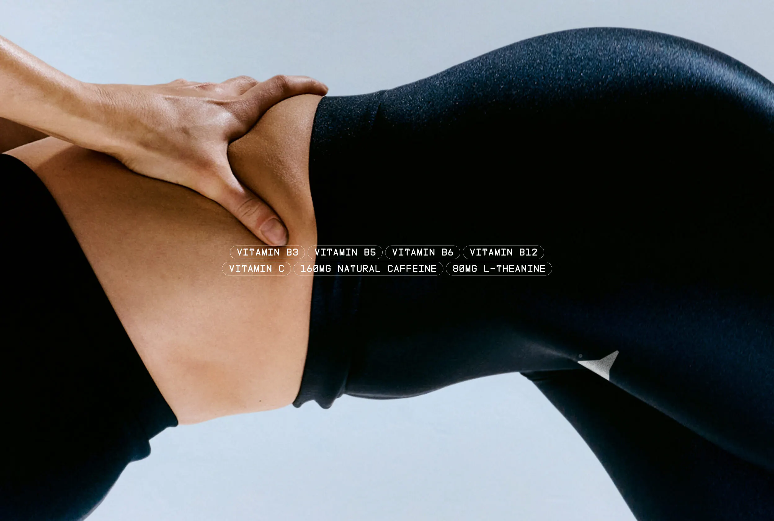 Close-up of a woman's torso in athletic wear with ingredient callout pills overlaid: Vitamin B3, B5, B6, B12, Vitamin C, 160MG Natural Caffeine, 80MG L-Theanine