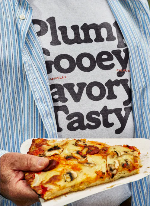 A person in a blue striped shirt holds a slice of square pizza. Underneath, a white t-shirt is visible printed with the stacked words "Plump / Gooey / Savory / Tasty" in the Ramboia Bold typeface. Small red text reads "Los Angeles, California."