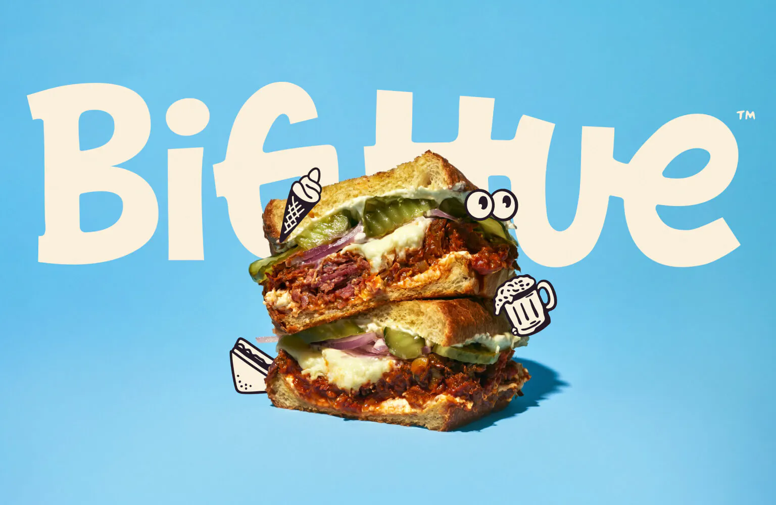 Light blue background with the large Big Hue wordmark in cream behind a stacked, cross-cut sandwich. Small hand-drawn sticker illustrations — an ice cream cone, eyes mascot, beer mug, and hot dog — float around the food.