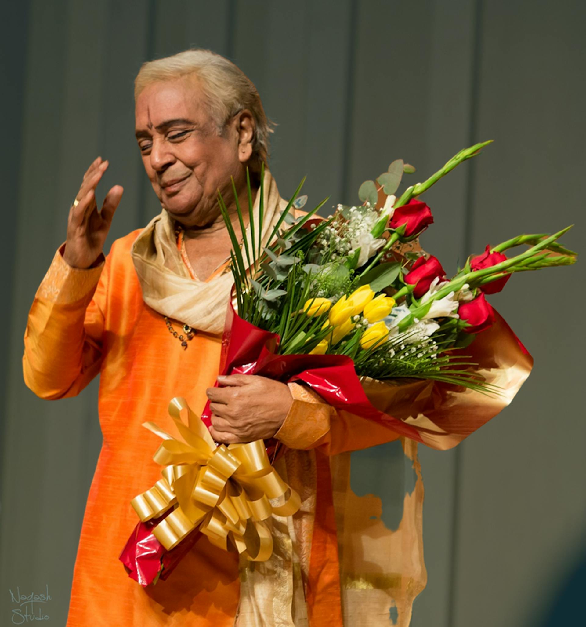 Pt. Birju Maharaj Ji holding a bouquet of flowers