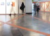 Architectural intervention  'Telon' by Artist Henry Coleman installed at Mexico city Metro Station Auditorio with vibrant orange vinyl crosses applied to a large vitrine with a woman looking inside whilst blurred figures move past