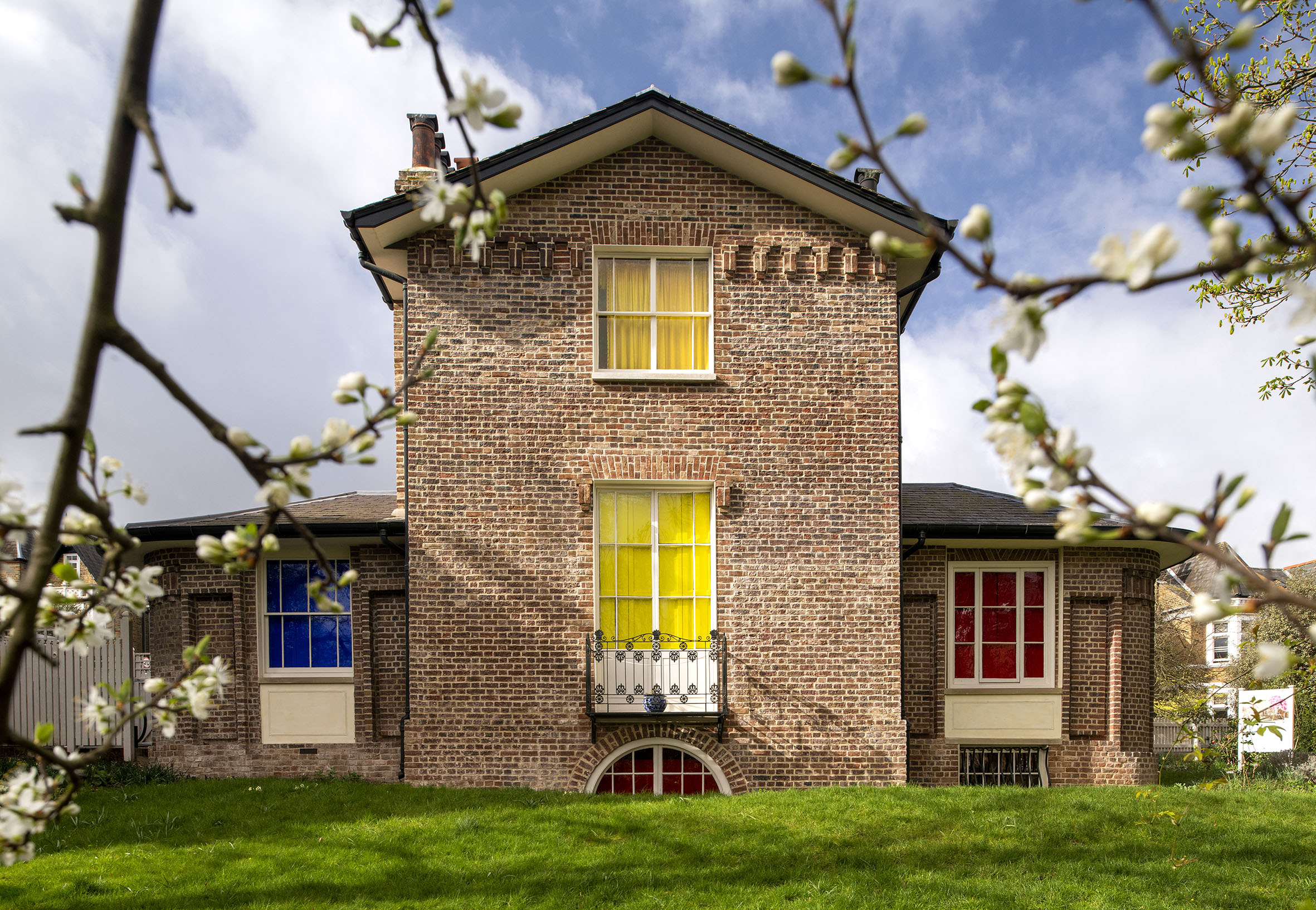 The effects', architectural installation by artist Henry Coleman. Garden view of  JMW Turner's House, Sandycombe Lodge with windows colored with Red, yellow and blue framed by blossoming tree