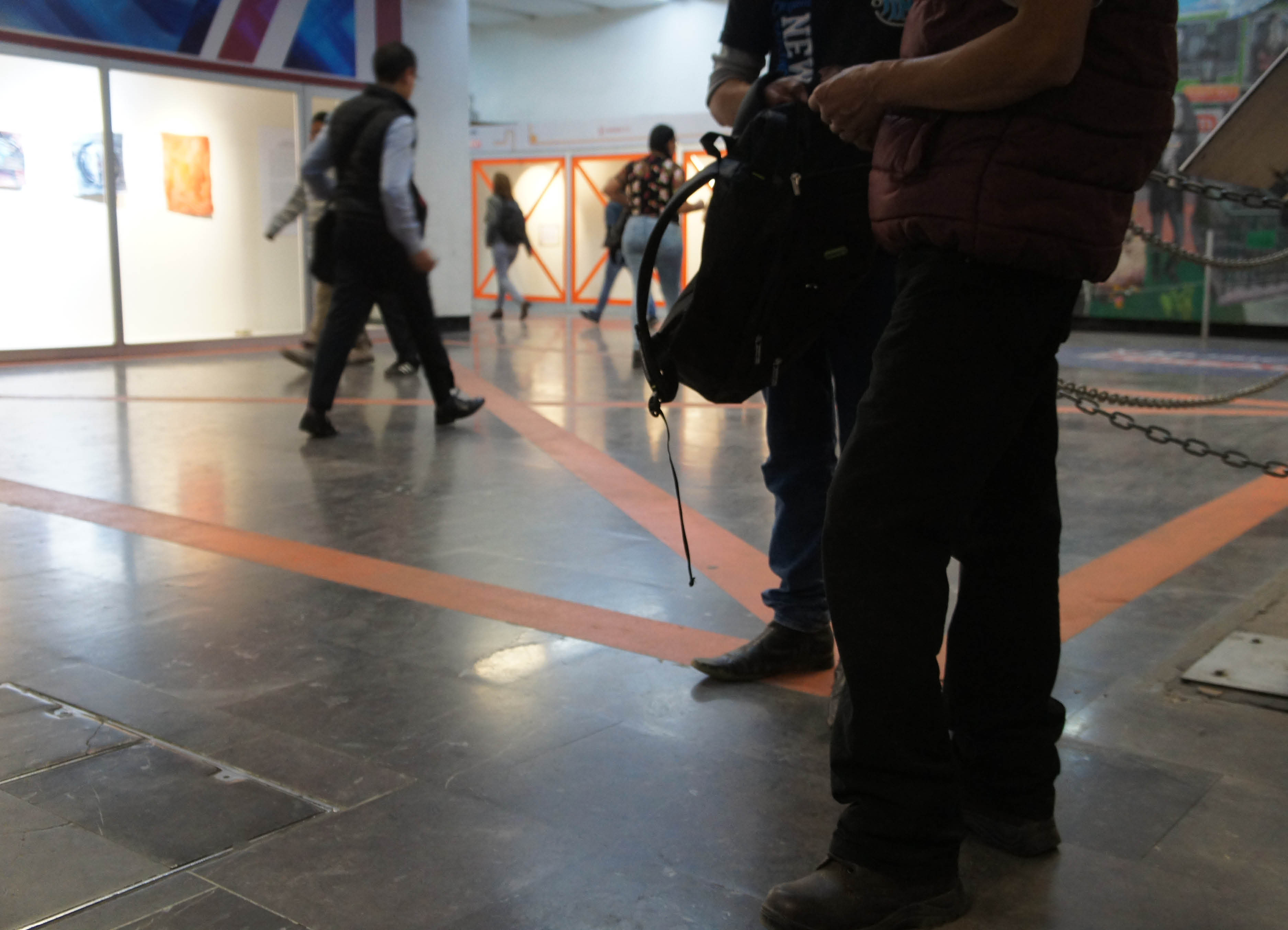 Public Sculpture 'Telon' by Artist Henry Coleman installed at Mexico city Metro Station Auditorio with vibrant orange vinyl crosses applied to a large vitrine and marking a cross on the floor with figures silhouetted in front move past