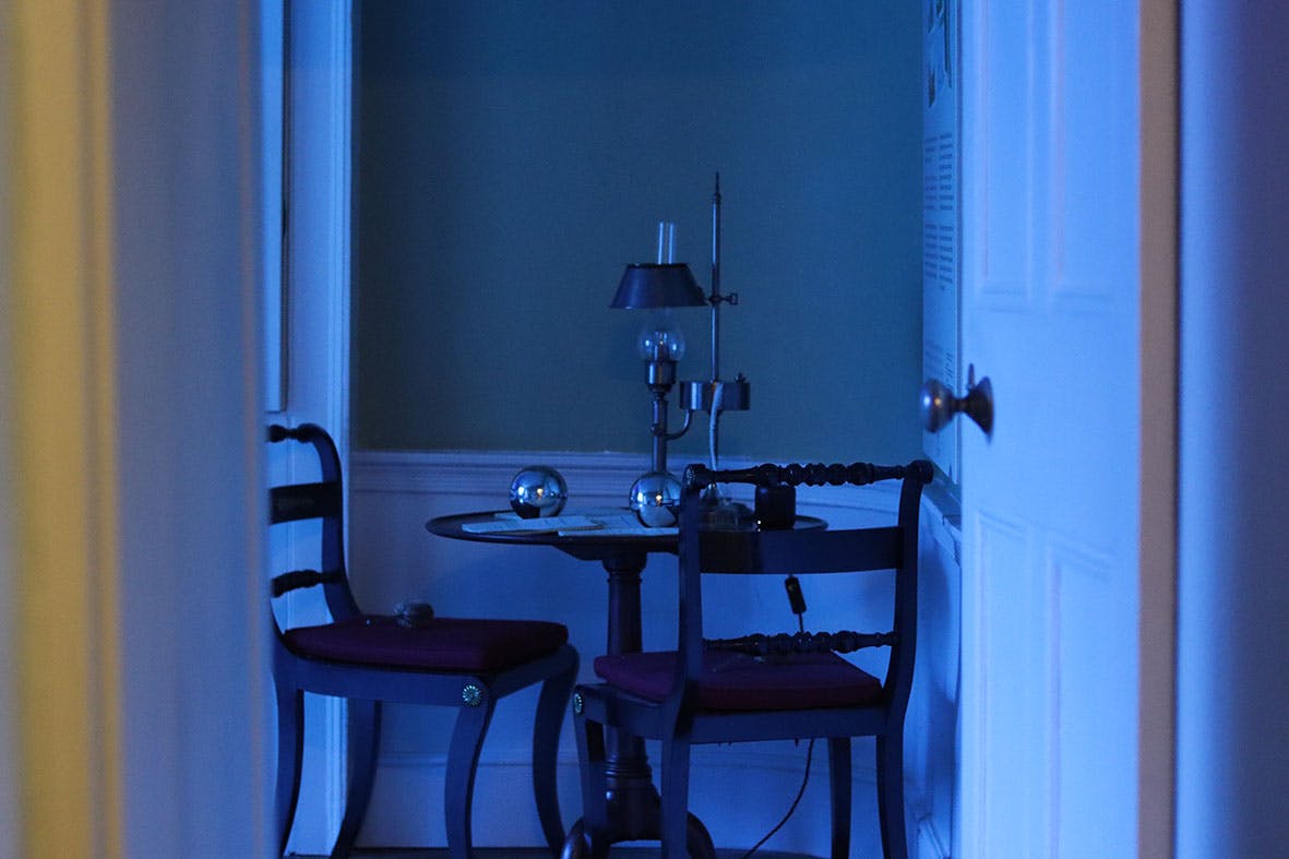 The effects', Sculptural installation by artist Henry Coleman. Drawing room of JMW Turner's House, Sandycombe Lodge bathed in blue colored light viewed through a doorway, two reflective globes and a lamp  sit on an ornate table