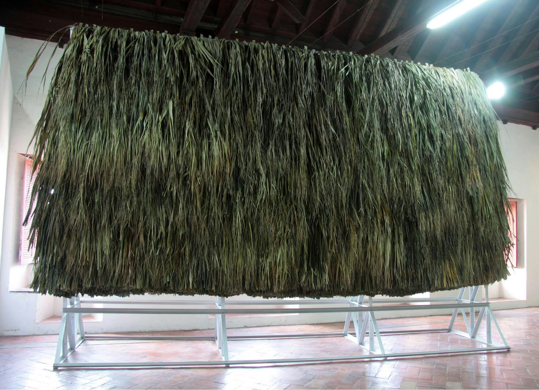 Decorated structure (productive public) by artist Henry Coleman, produced for Salon nacional de Artistas, Cartagena, Colombia, a large wall of palapa thatch is mounted onto decorated white aluminum frame