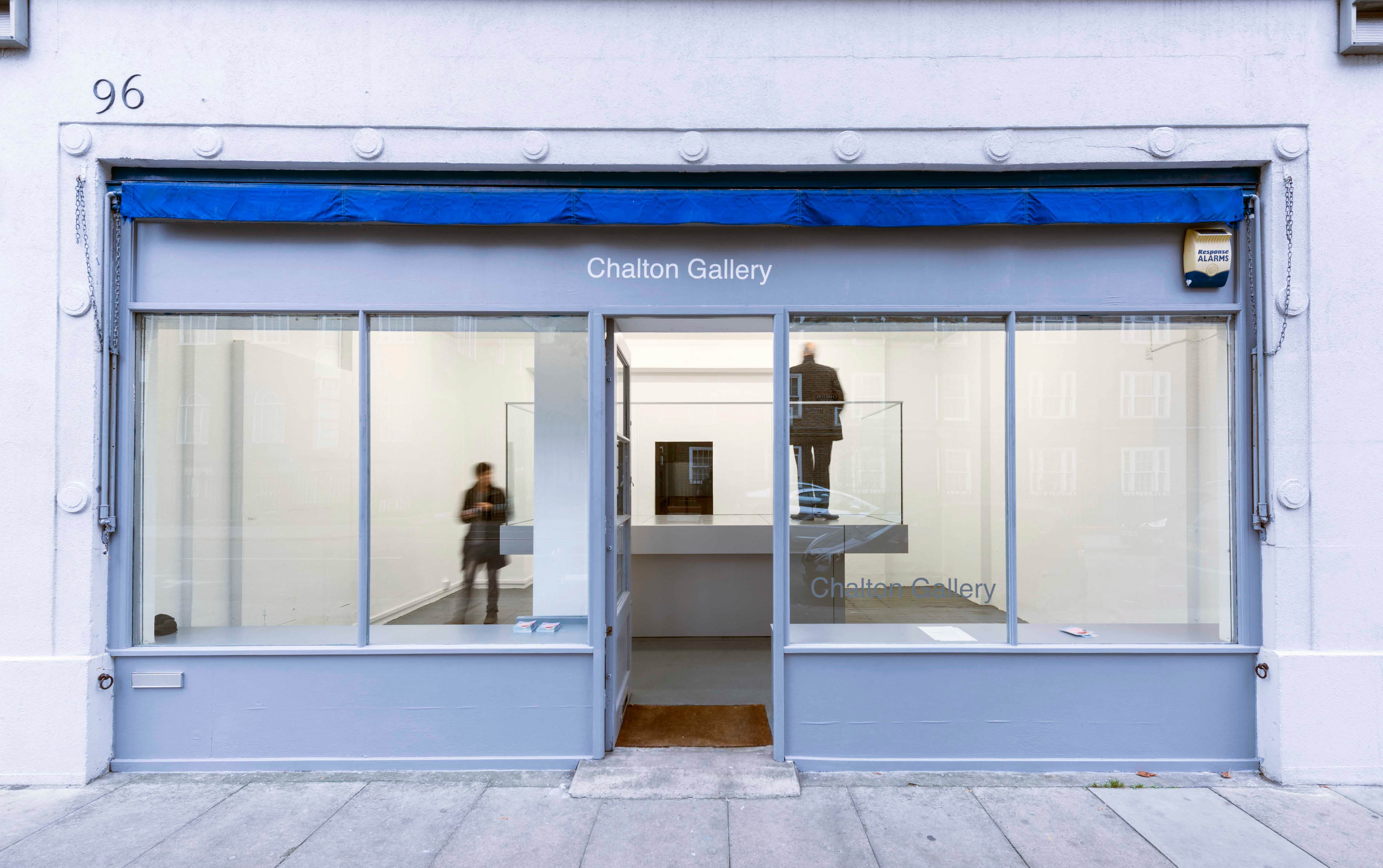 'My Sky' exhibition  by artist Henry Coleman at Chalton Street gallery, glazed balcony sculpture filling the gallery with a man standing on the platform watching the film and another walking to the side