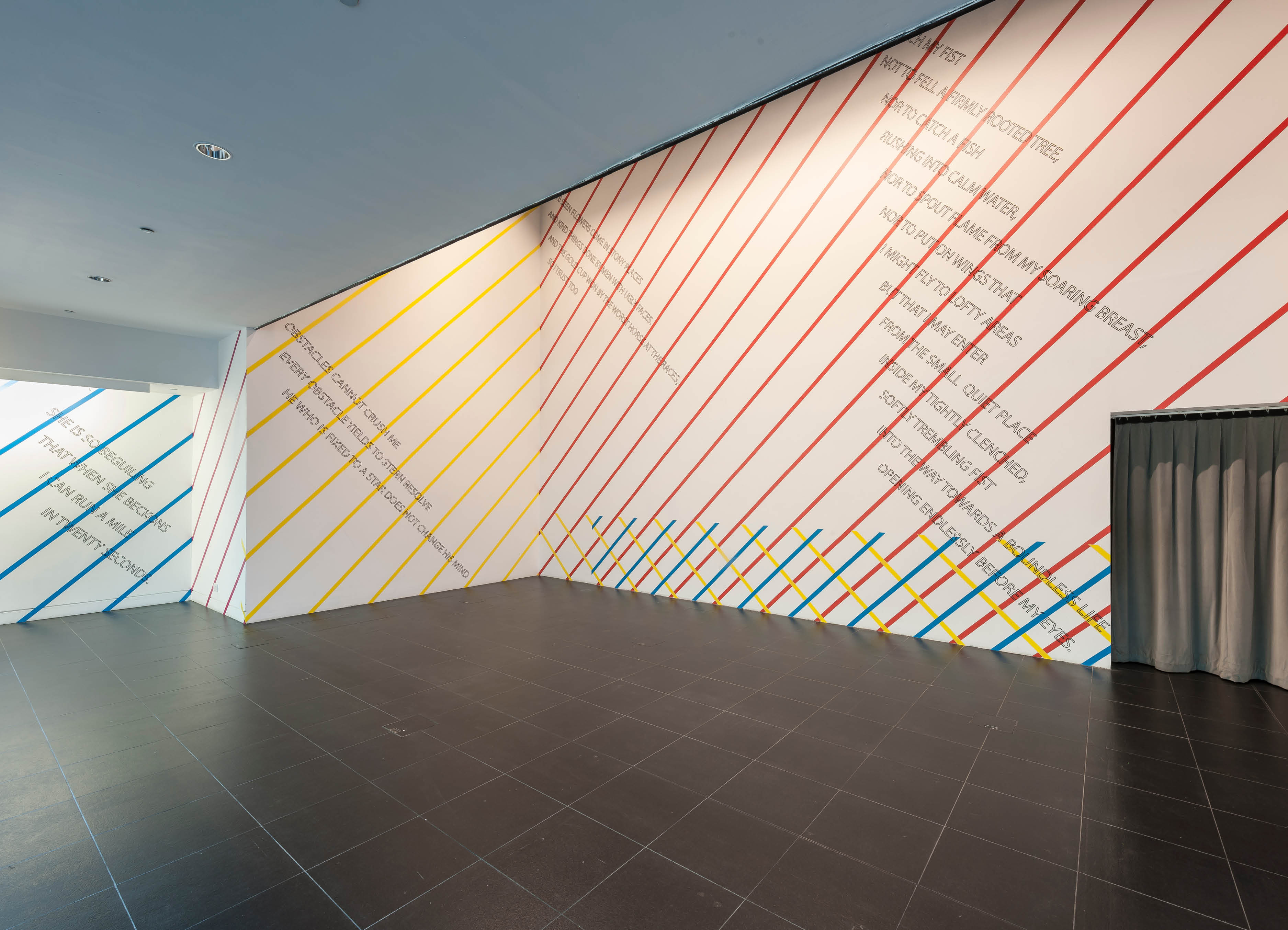 Winning words by Henry Coleman and Graham Reid, Olympic artwork project for the London 2012 Olympics, primary colored vinyl stripes run diagonally and overlap each other and poetic texts in a large gallery space