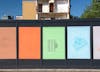 Life on other lines' by artist Henry Coleman. Installation of brightly colored posters based on drawings of the Polygon Estate, Somers Town by Architect Peter Tabori, pasted across a building hoarding against a bright blue sky
