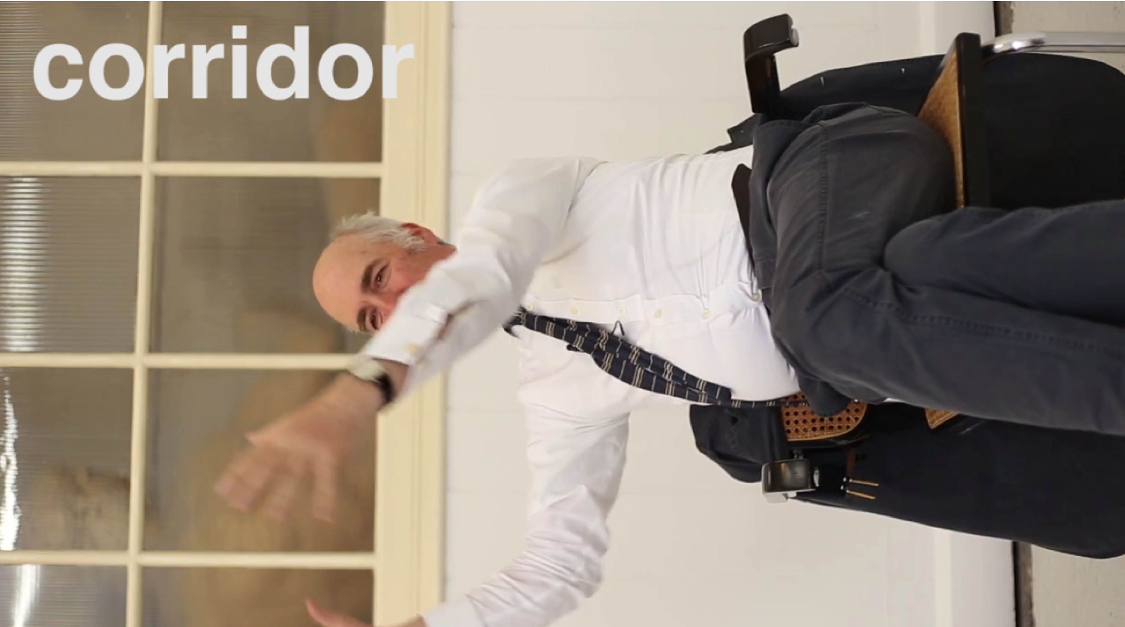 'The Greater Order', Sculptural installation by artist Henry Coleman across the Royal Academy buildings, London. Film still from 'Corridor to Campus' filmed interview with Charles Suarez Smith shows interviewee seated in a Marcel Breuer Cesca chair with the image tilted 90 degrees and the word Corridor showing in the top left corner 