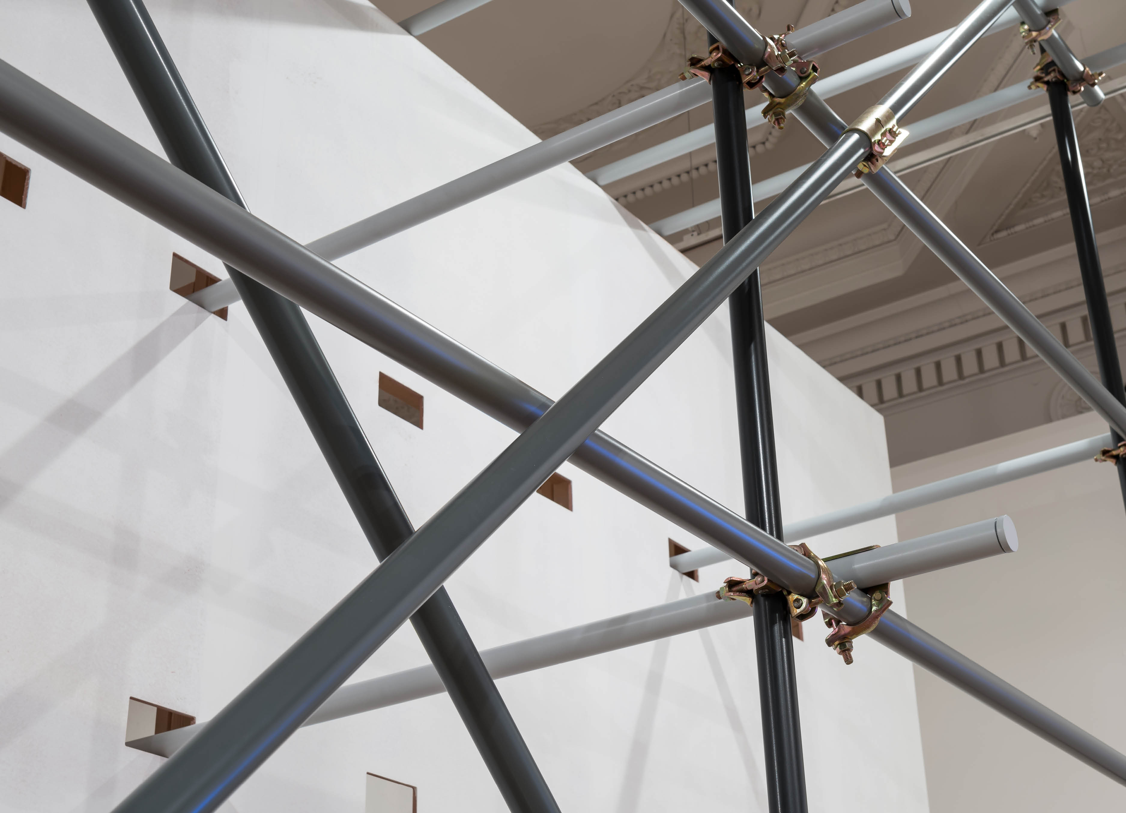 'Ornament, Work'  by Henry Coleman,  produced for the Royal Academy Premiums exhibition, detail of a  temporary wall structure with decorative scaffolding  in tones of powder coated grey 