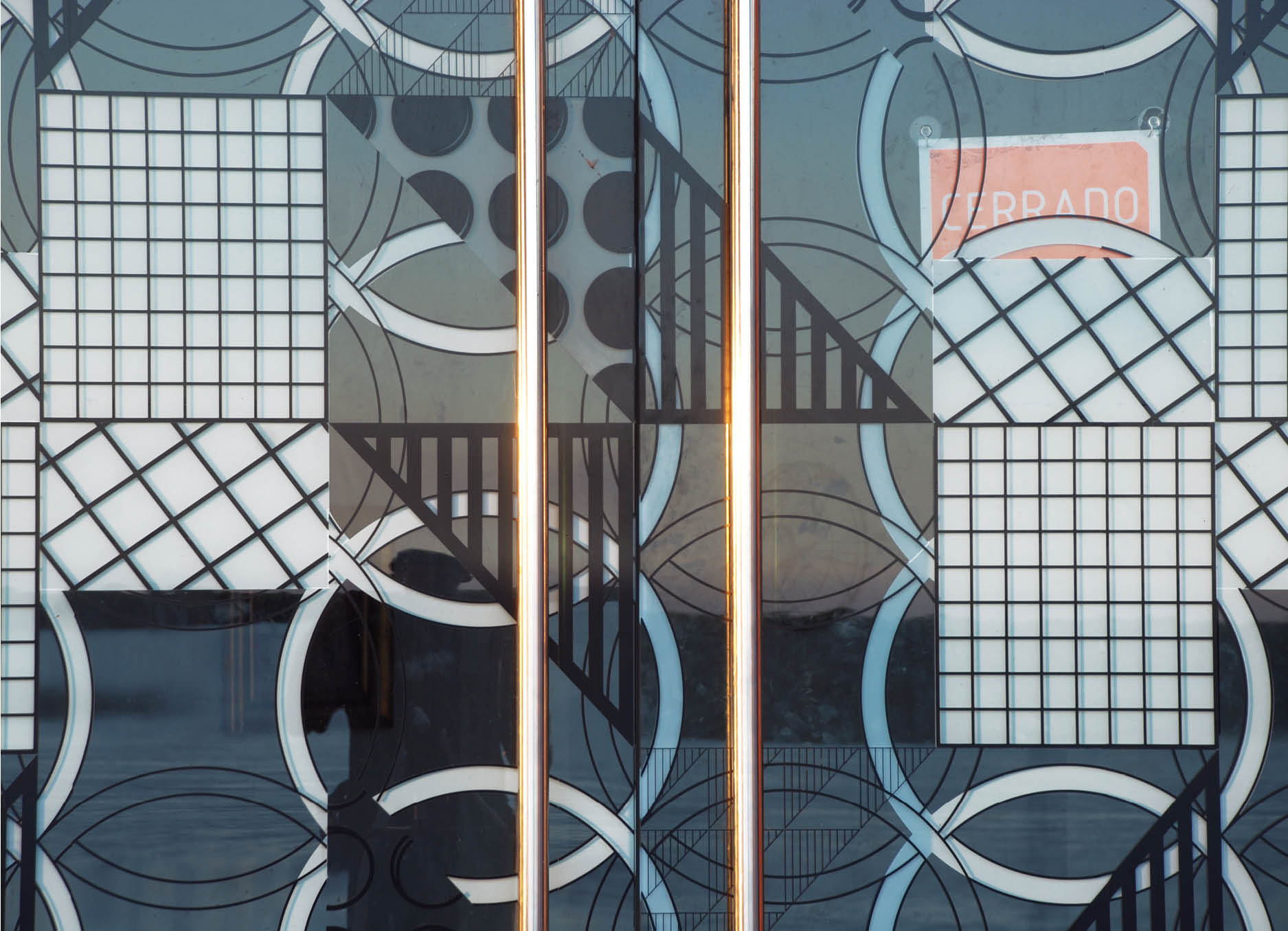 'Telon' Public sculpture  by Henry Coleman and Cristina Schiavi, installed at the MACRO in Rosario Argentina, Intricate geometric patterns in black and white applied to a window with a red sign spelling out cerrado behind the glass