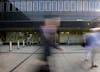 Port Portal Piscator' Vinyl installation by artist Henry Coleman of yellow vinyl crosses across the modernist façade of old Euston station forecourt building by Seifert and Partners, now destroyed, with blurred figures walking in the foreground