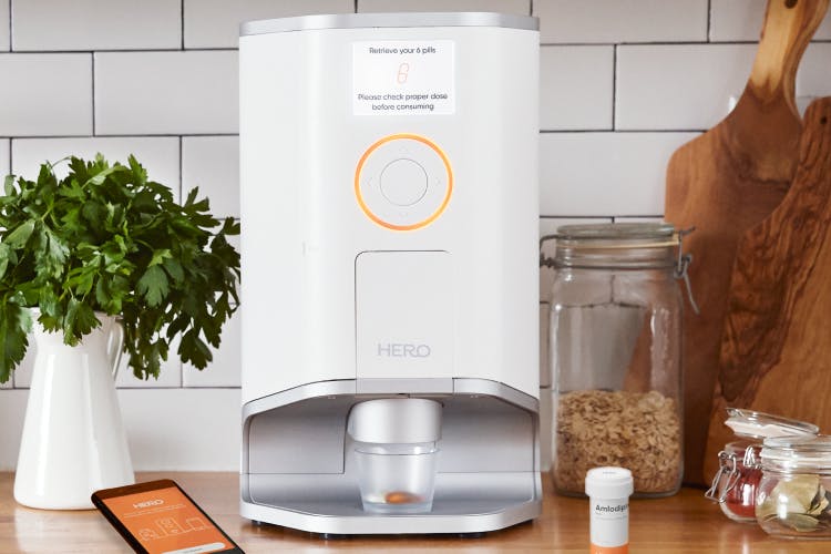 Hero's award-winning smart dispenser and medication management app on a kitchen table 