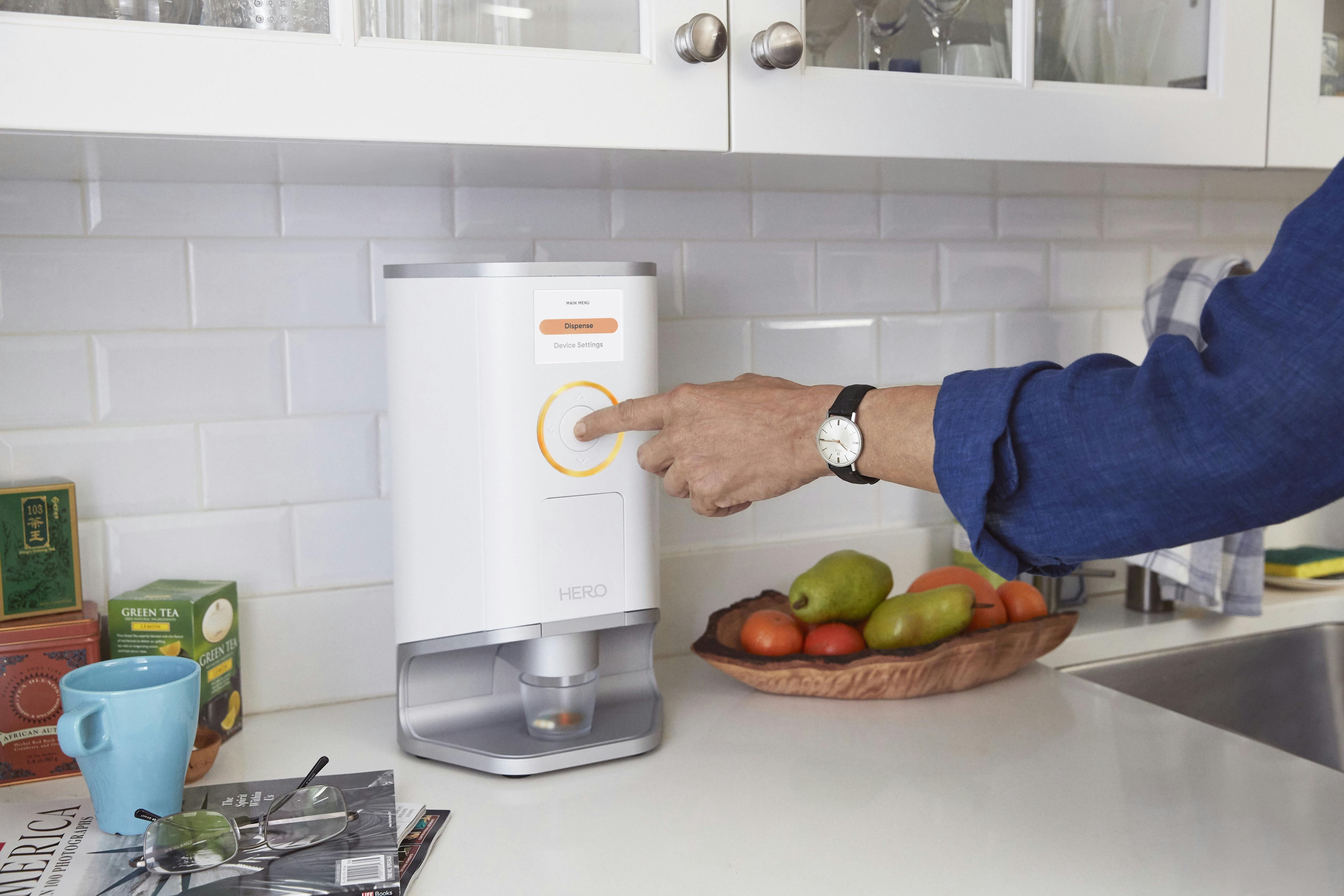 Person pressing the center button of the Hero pill dispenser 