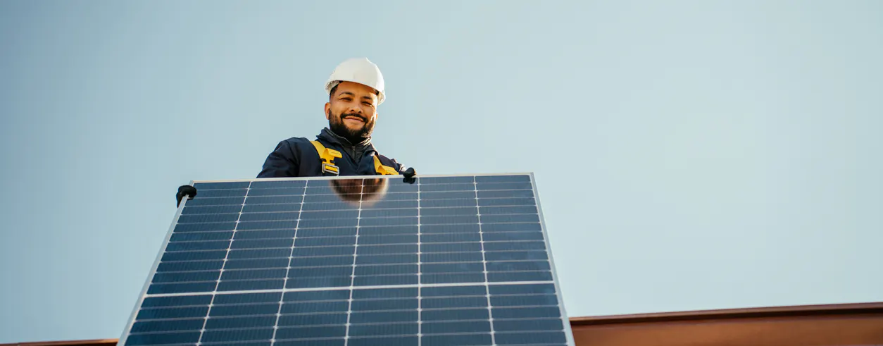 Un technicien en train d'installer des panneaux solaires photovoltaïques sur le toit d'une maison