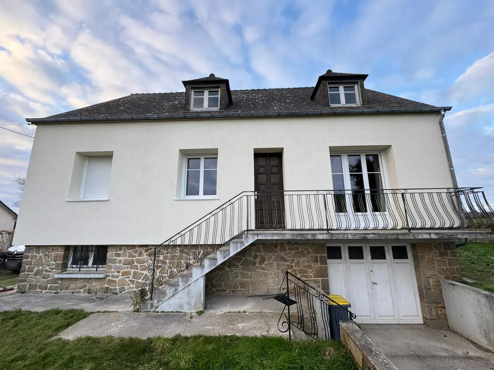 Façade de maison isolée par l'extérieur, enduit blanc cassé et soubassement en pierre