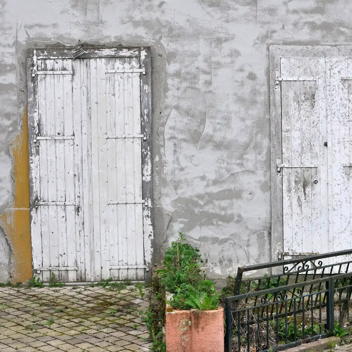 Façade d'une maison ancienne aux portes en bois écaillées