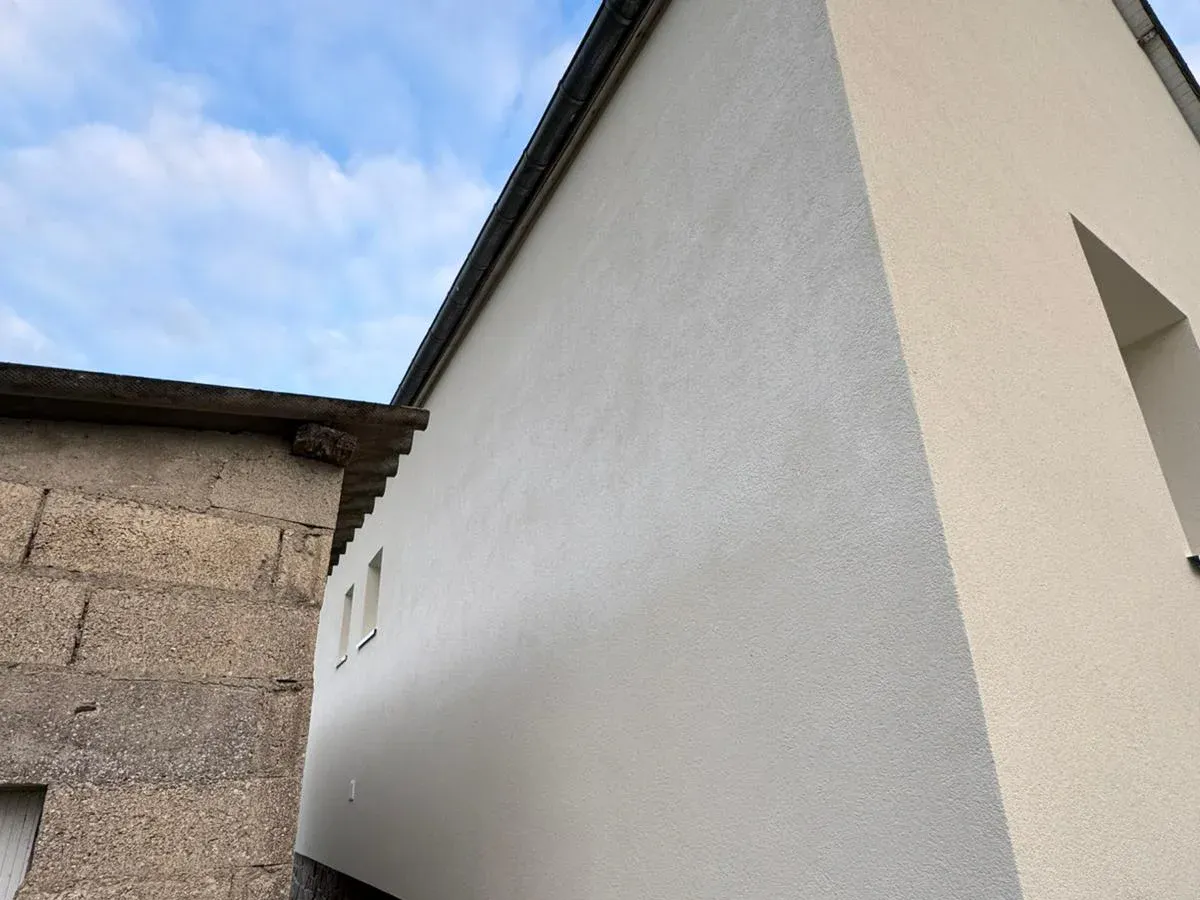 Maison isolée par l’extérieur dans le cadre d’une rénovation d’ampleur, Bretagne : mur en enduit fin et régulier, blanc cassé, vu en rasant