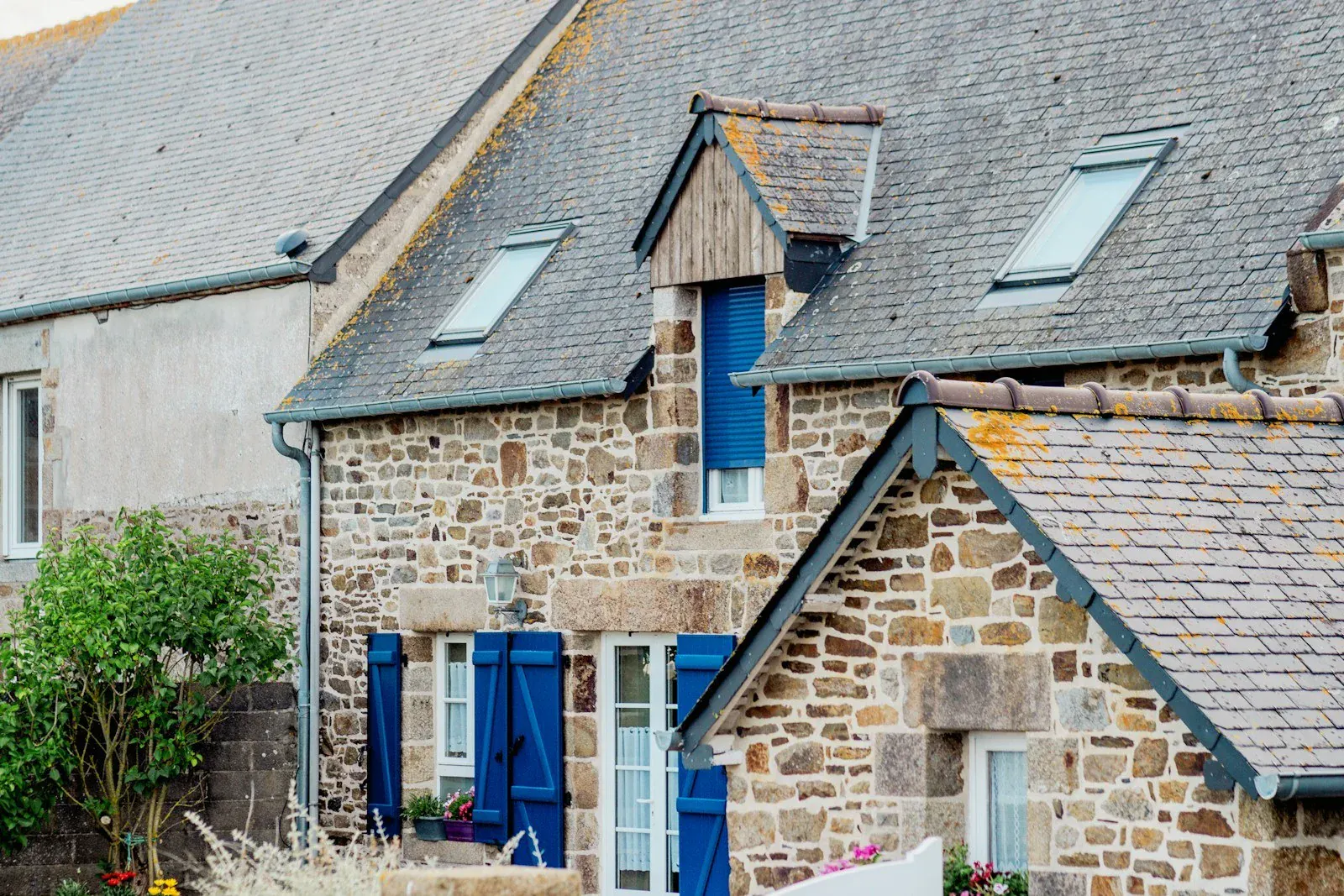 Maison ancienne en pierre aux volets bleus et toiture en ardoise